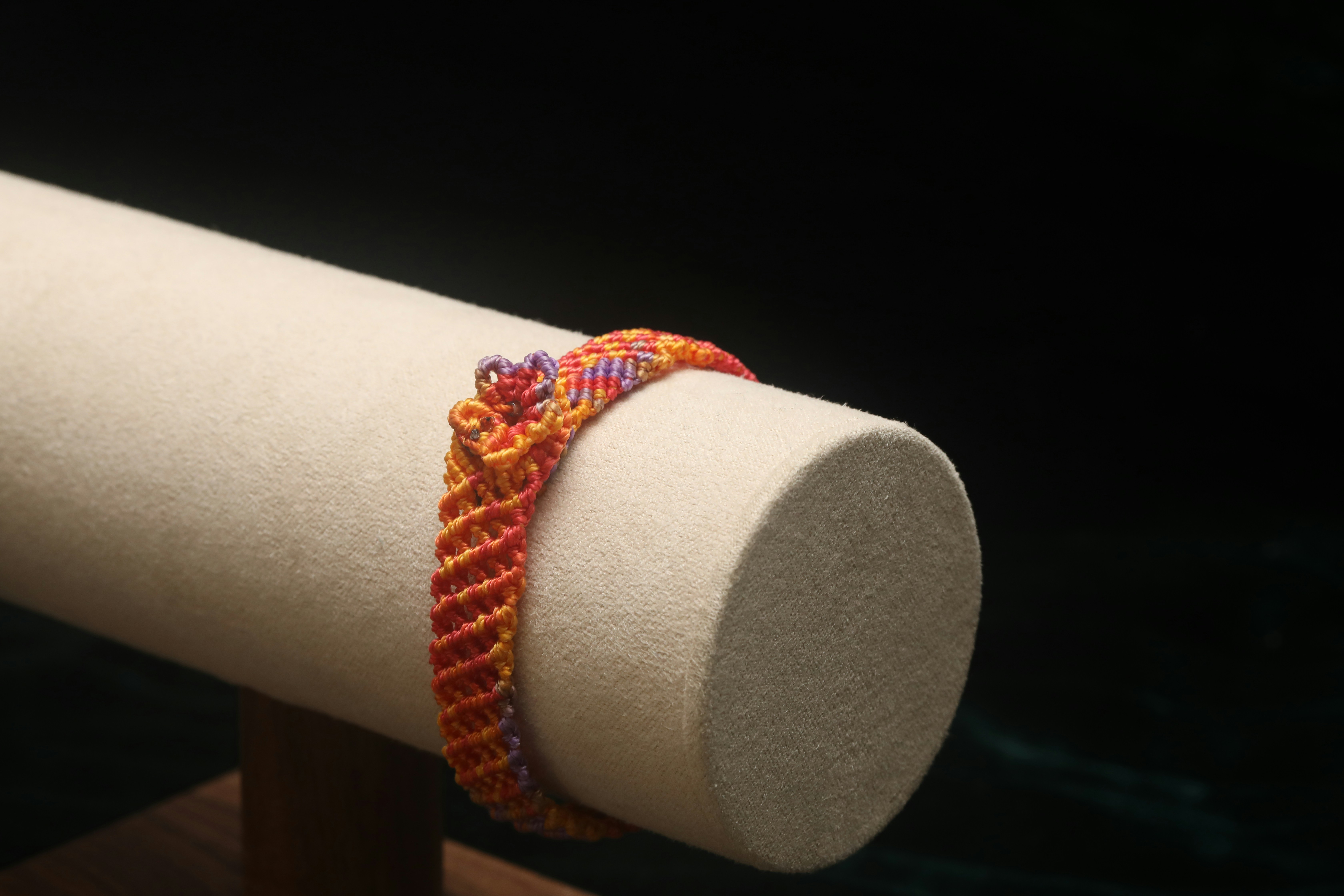 A colorful woven bracelet on display stand