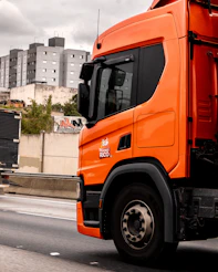 An orange truck drives down a highway