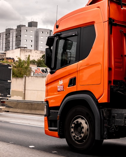 An orange truck drives down a highway.