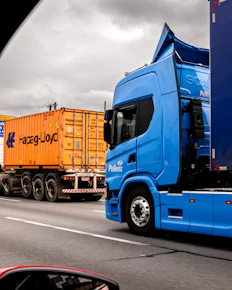 Two trucks on a highway under cloudy sky