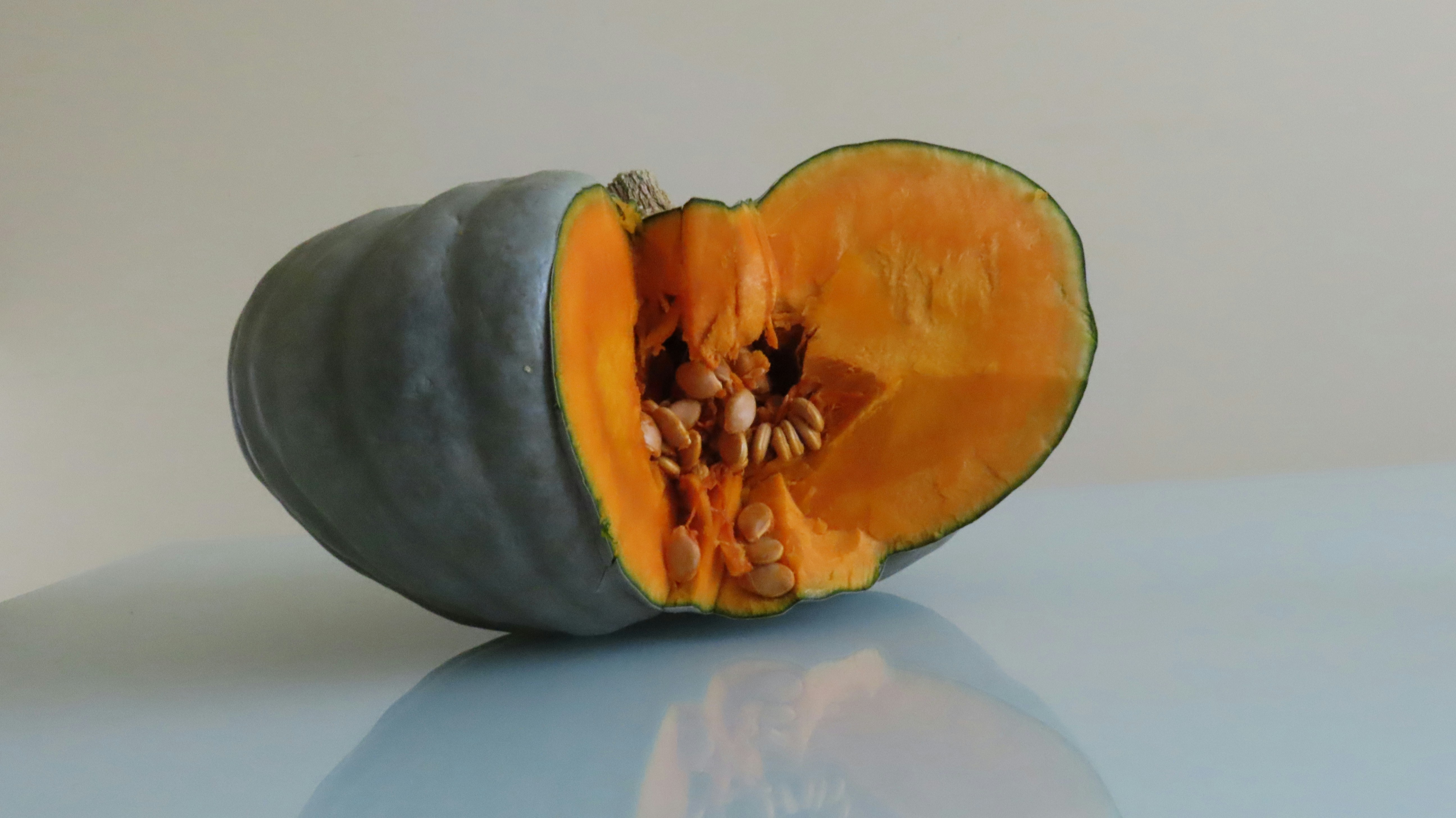 A halved blue pumpkin with bright orange flesh.