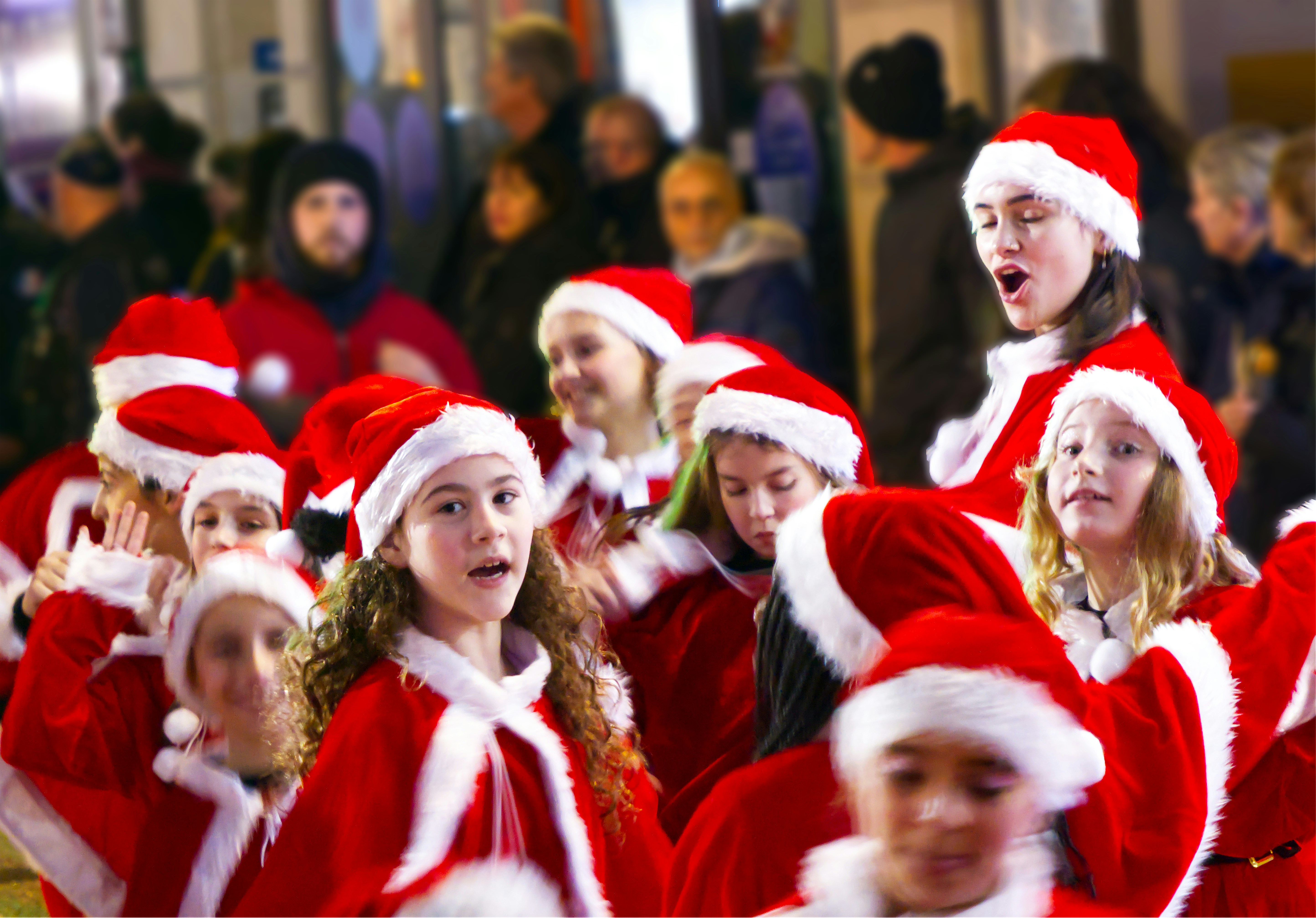 Crianças de chapéus de papai Noel e capas vermelhas comemorando