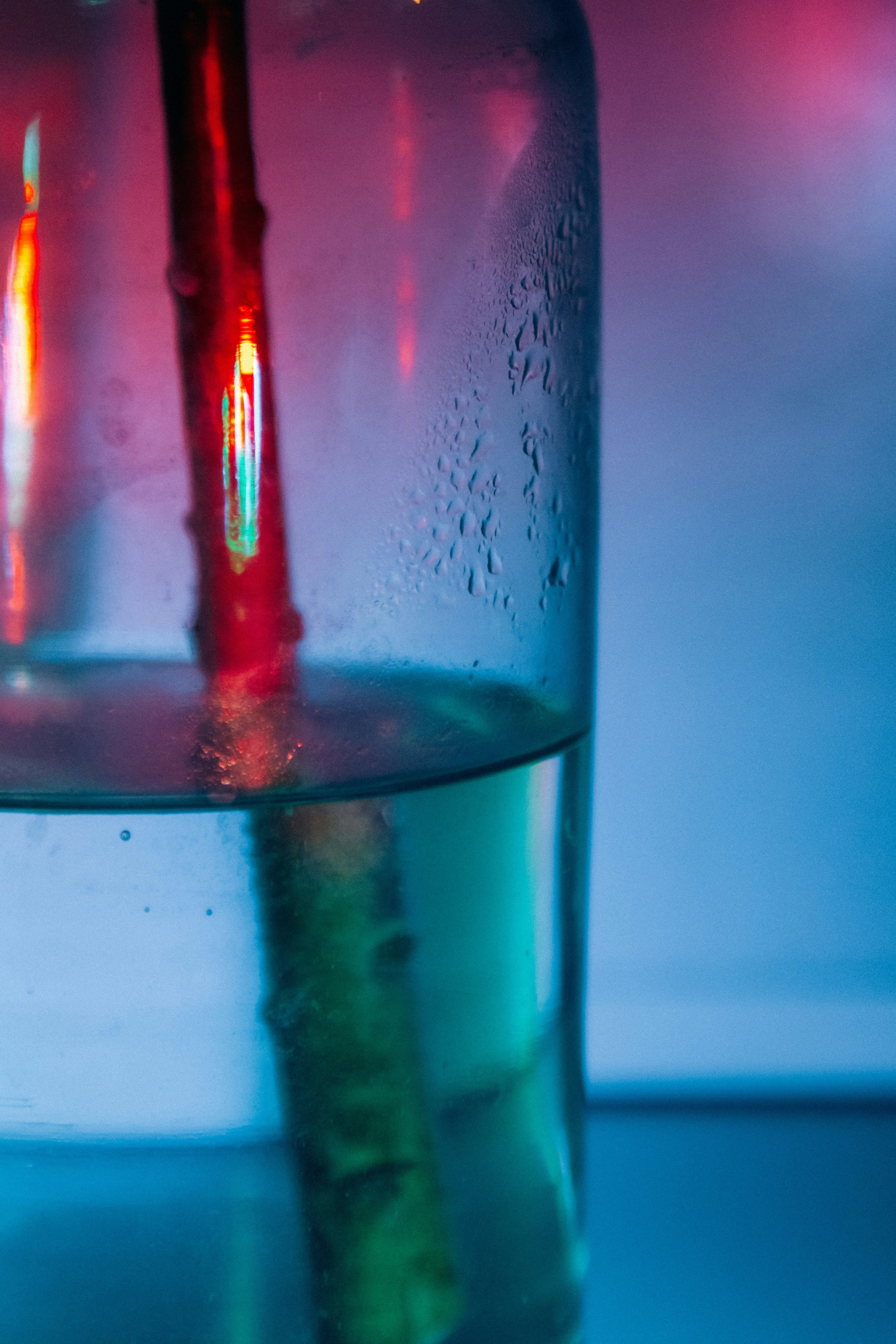 Red stem submerged in water with condensation on glass.