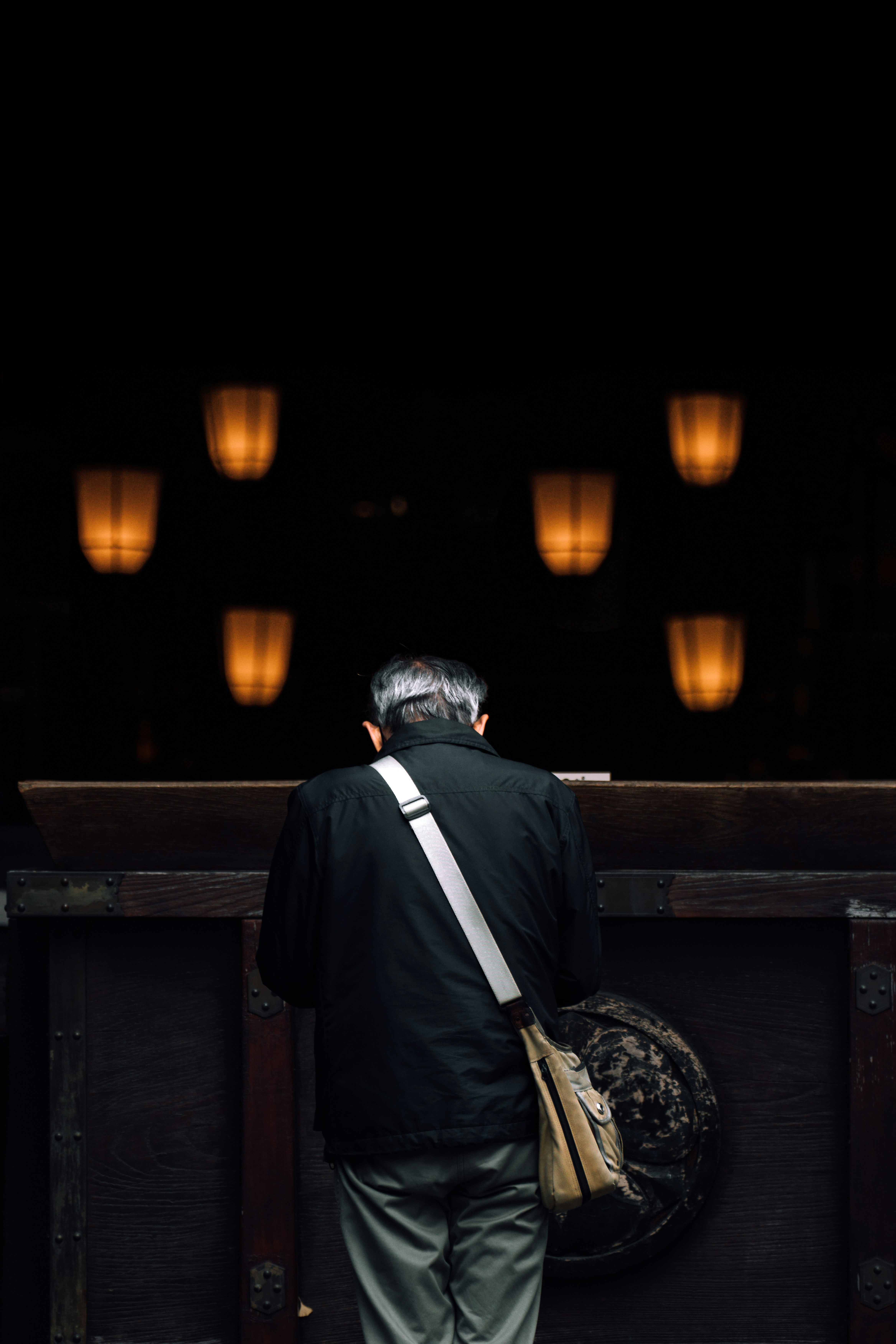 Man praying with lanterns in background