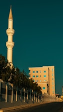Minaret of a mosque beside a modern building.