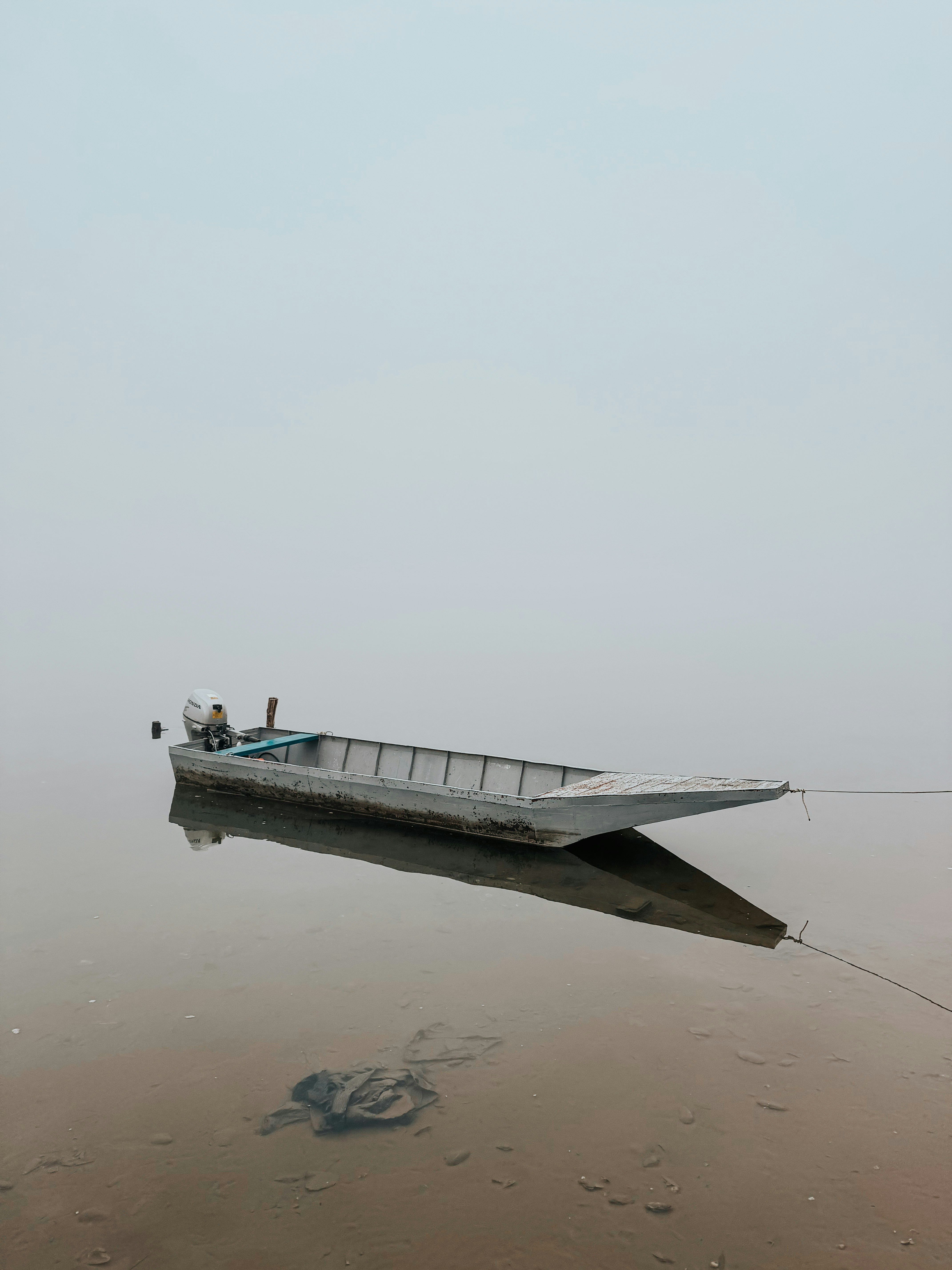 A lone boat floats on misty, calm water.