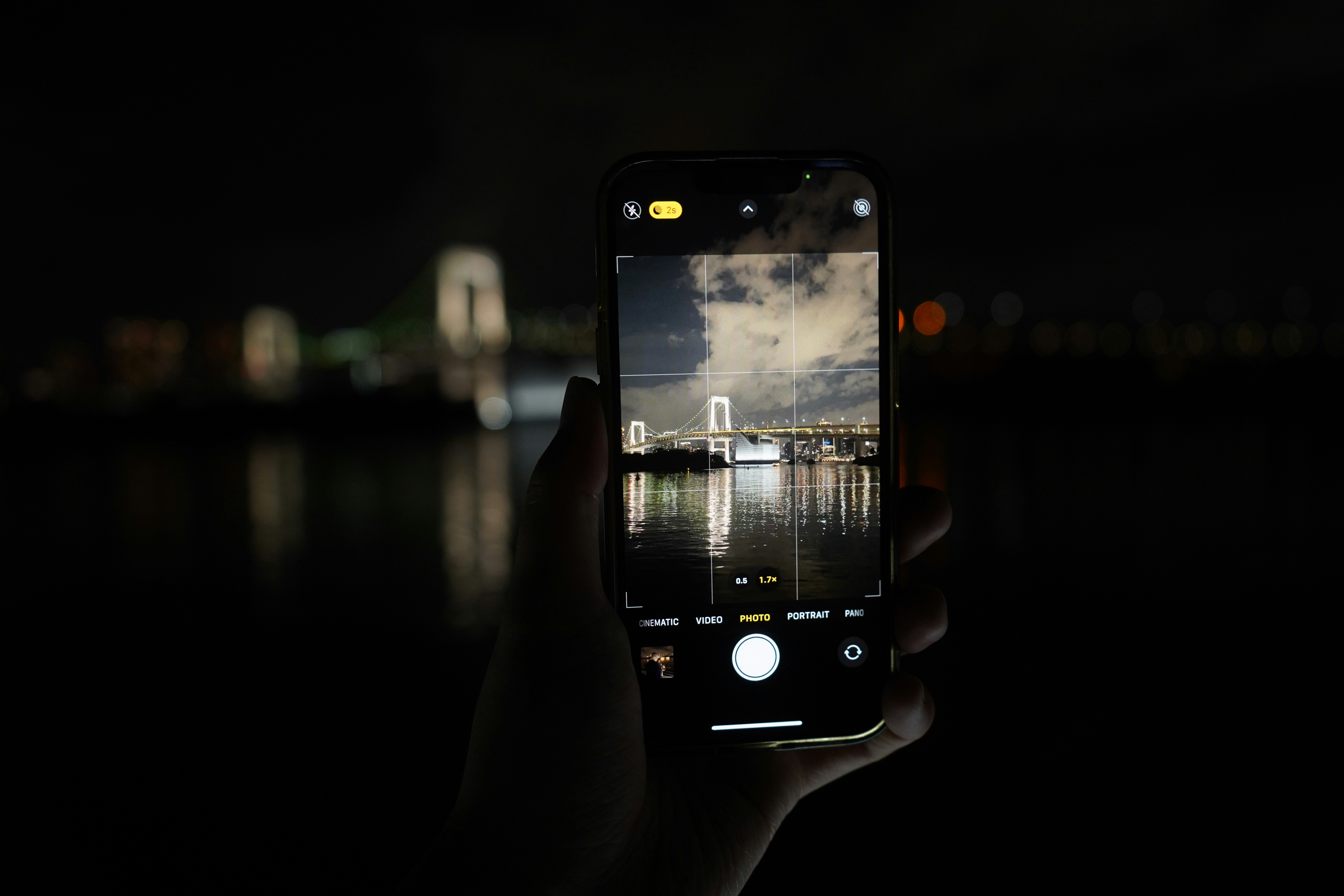 Hand holding smartphone capturing city lights at night
