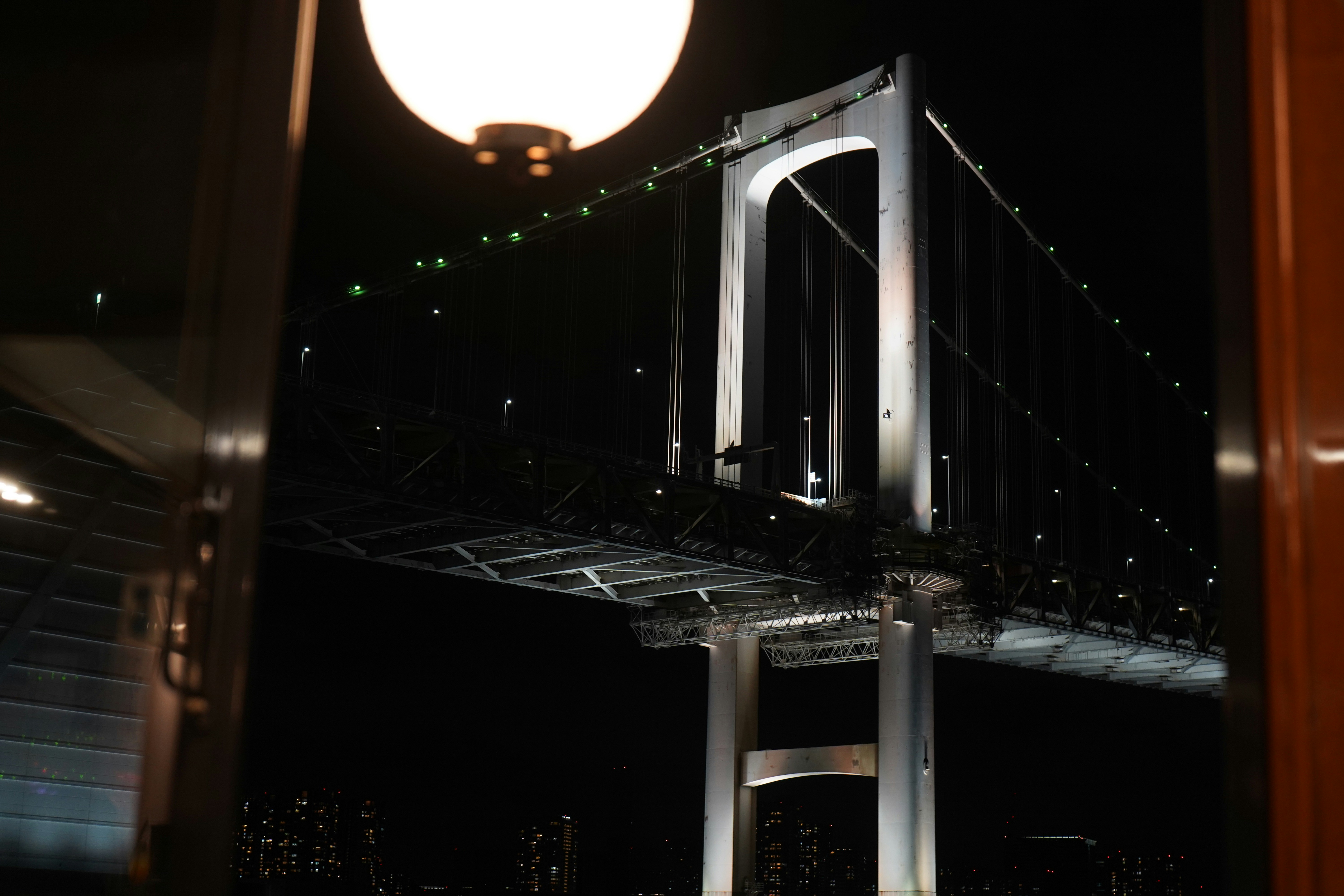 Illuminated suspension bridge at night with city lights.