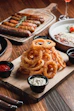 Golden onion rings with dipping sauces and sausages