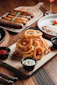 Golden onion rings with dipping sauces and sausages