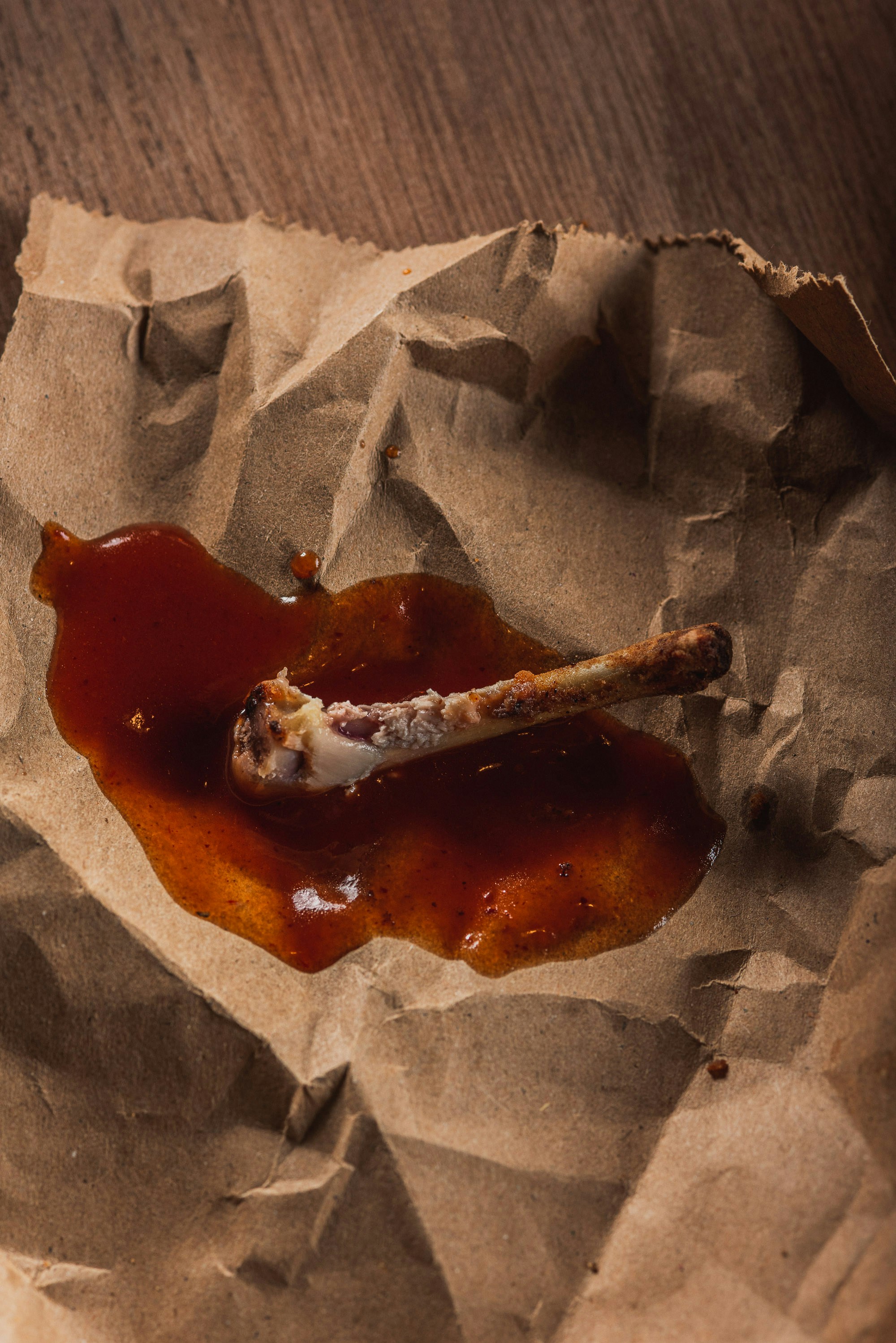 A chicken bone with sauce on crumpled paper