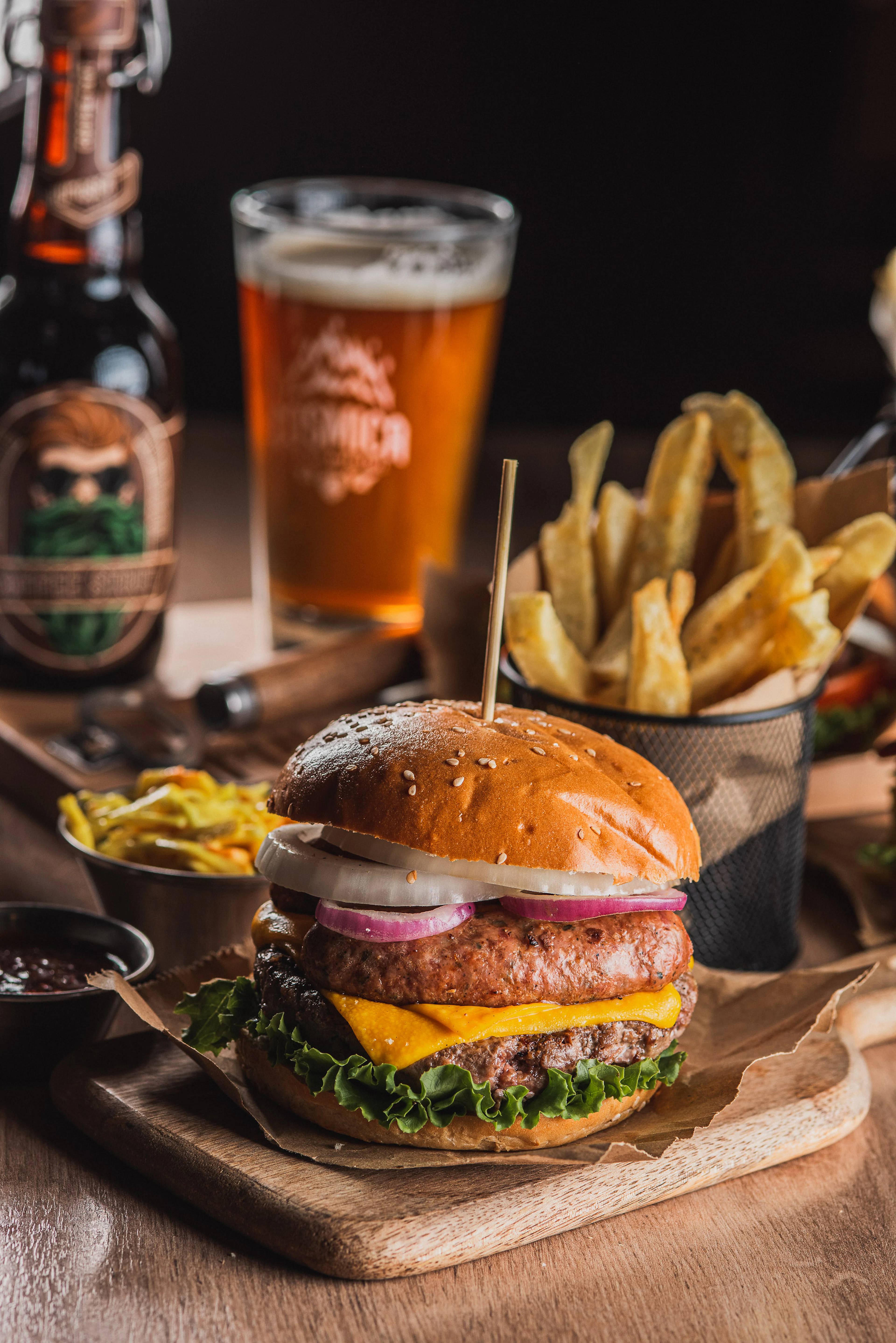 A burger with a basket of fries and a glass of beer on a pub table