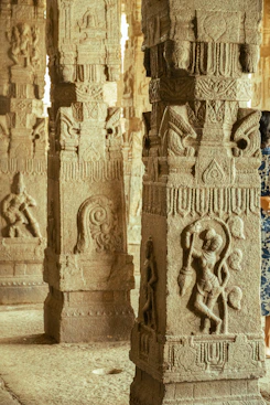 Ancient stone pillars with intricate carvings inside a temple.