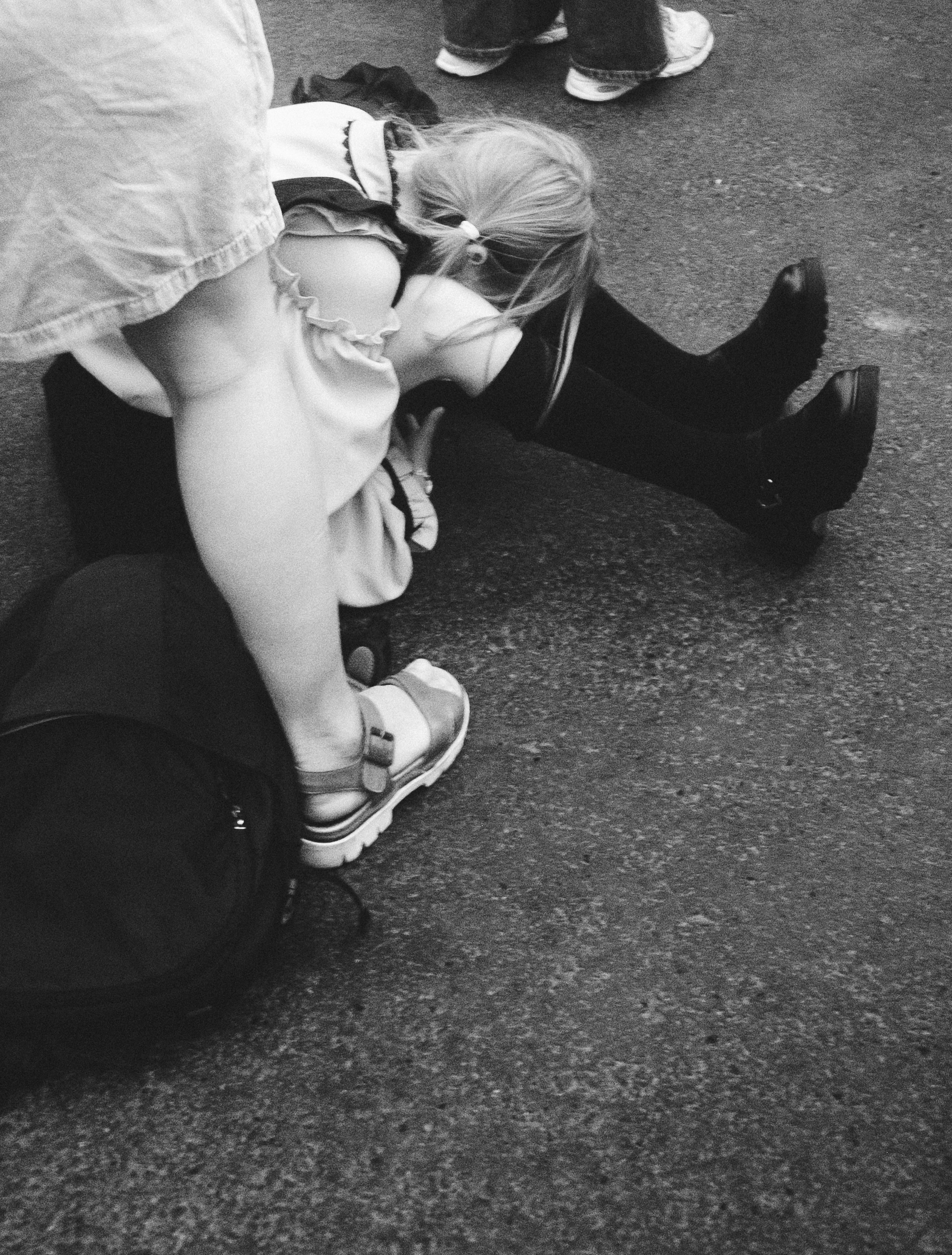 A child rests on the ground with adult legs around.