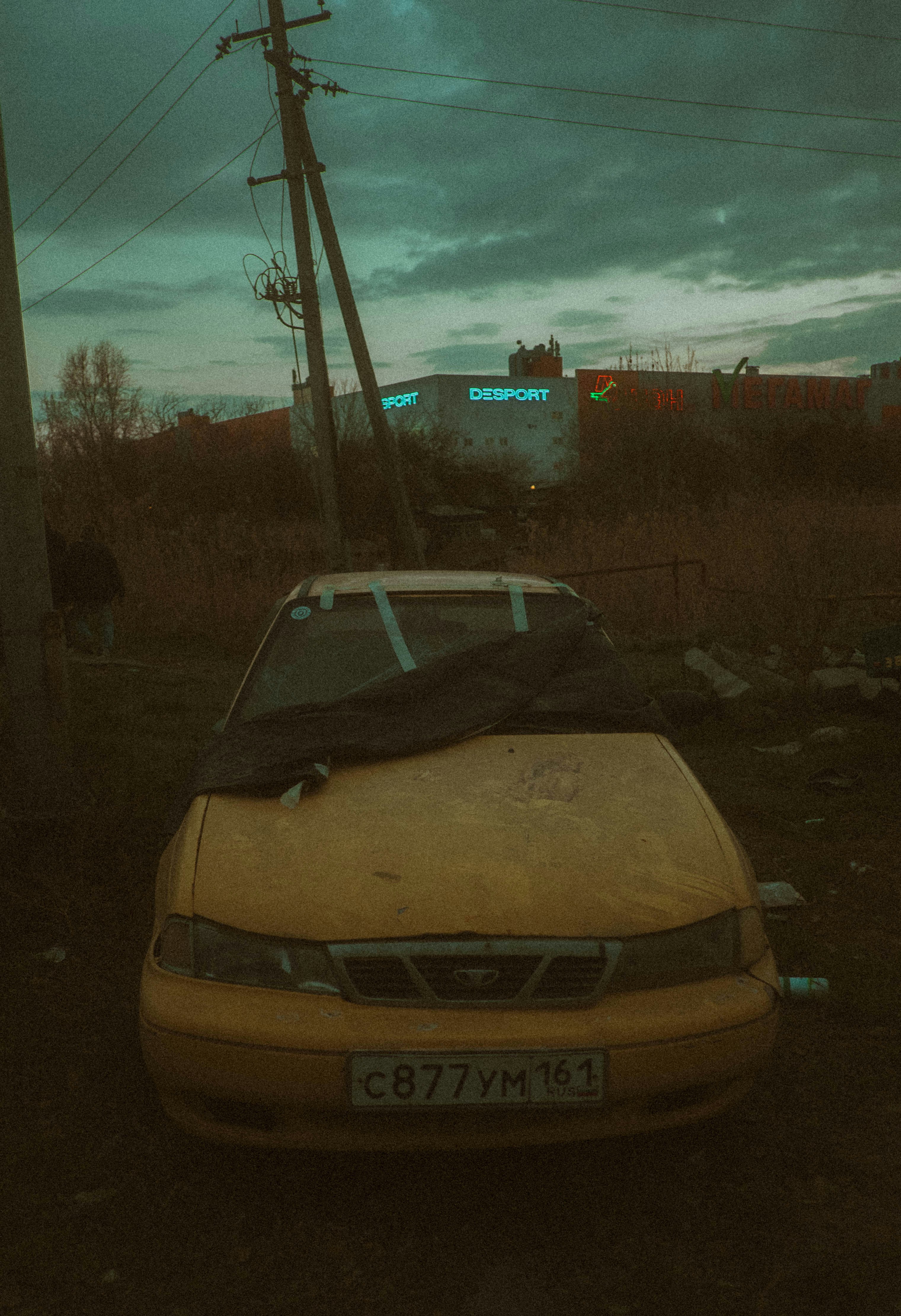 Yellow car covered with dark cloth outdoors