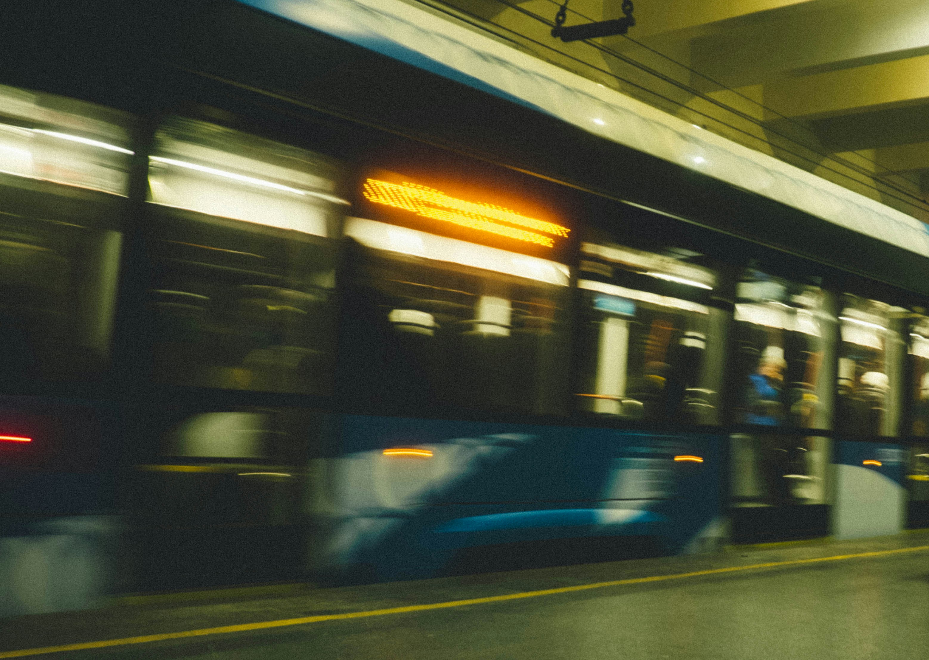 A blurred view of a moving tram at a station.