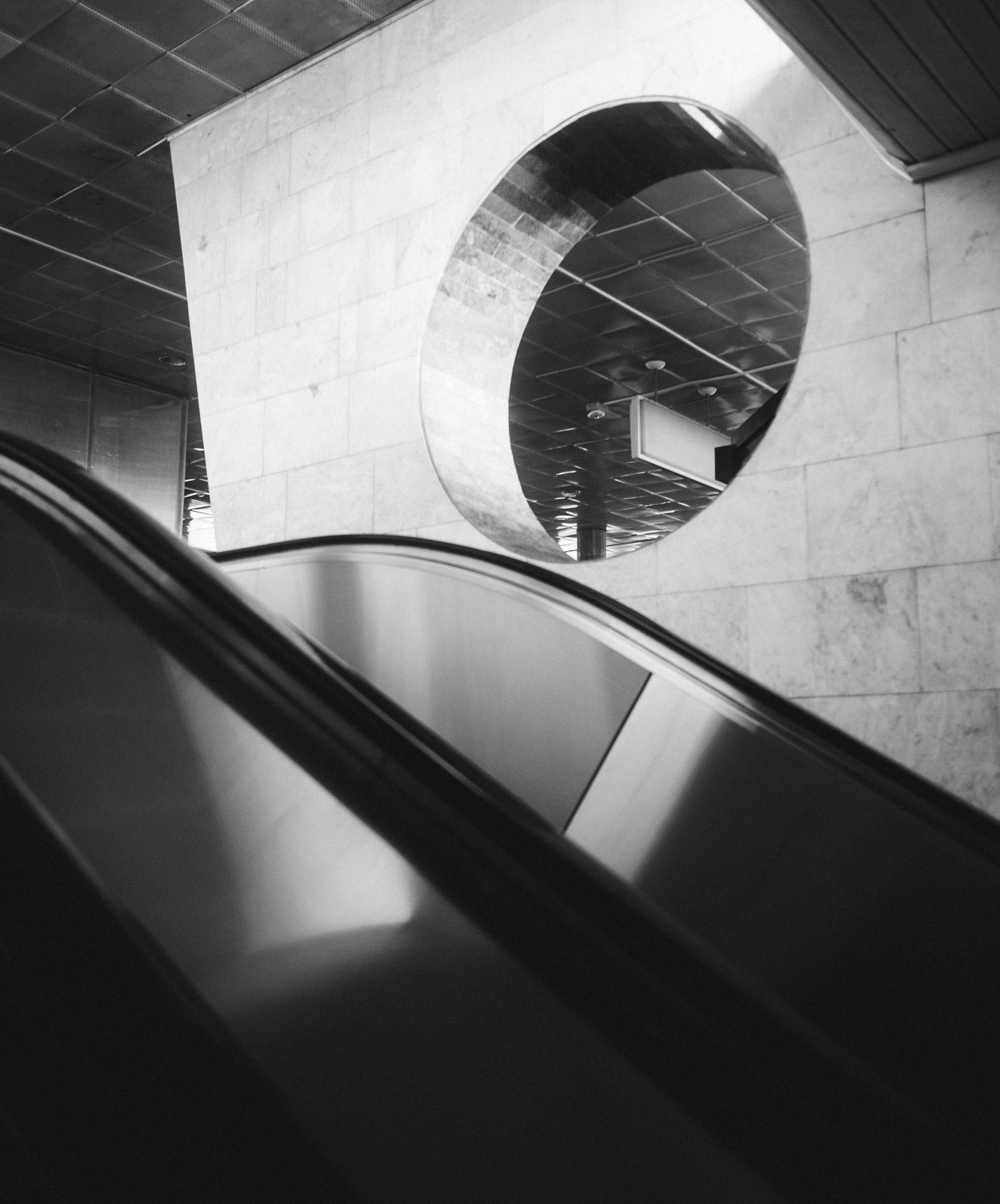 Escalator leading to a circular opening in wall