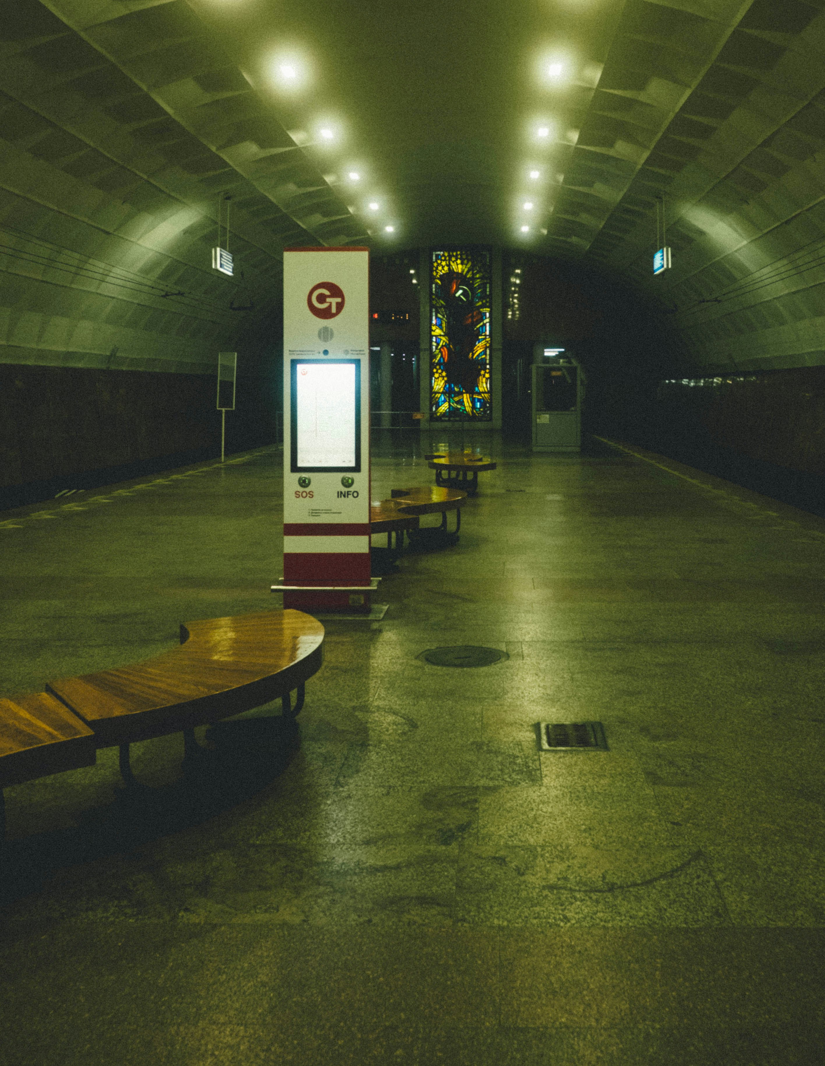 Empty subway station with benches and digital display.
