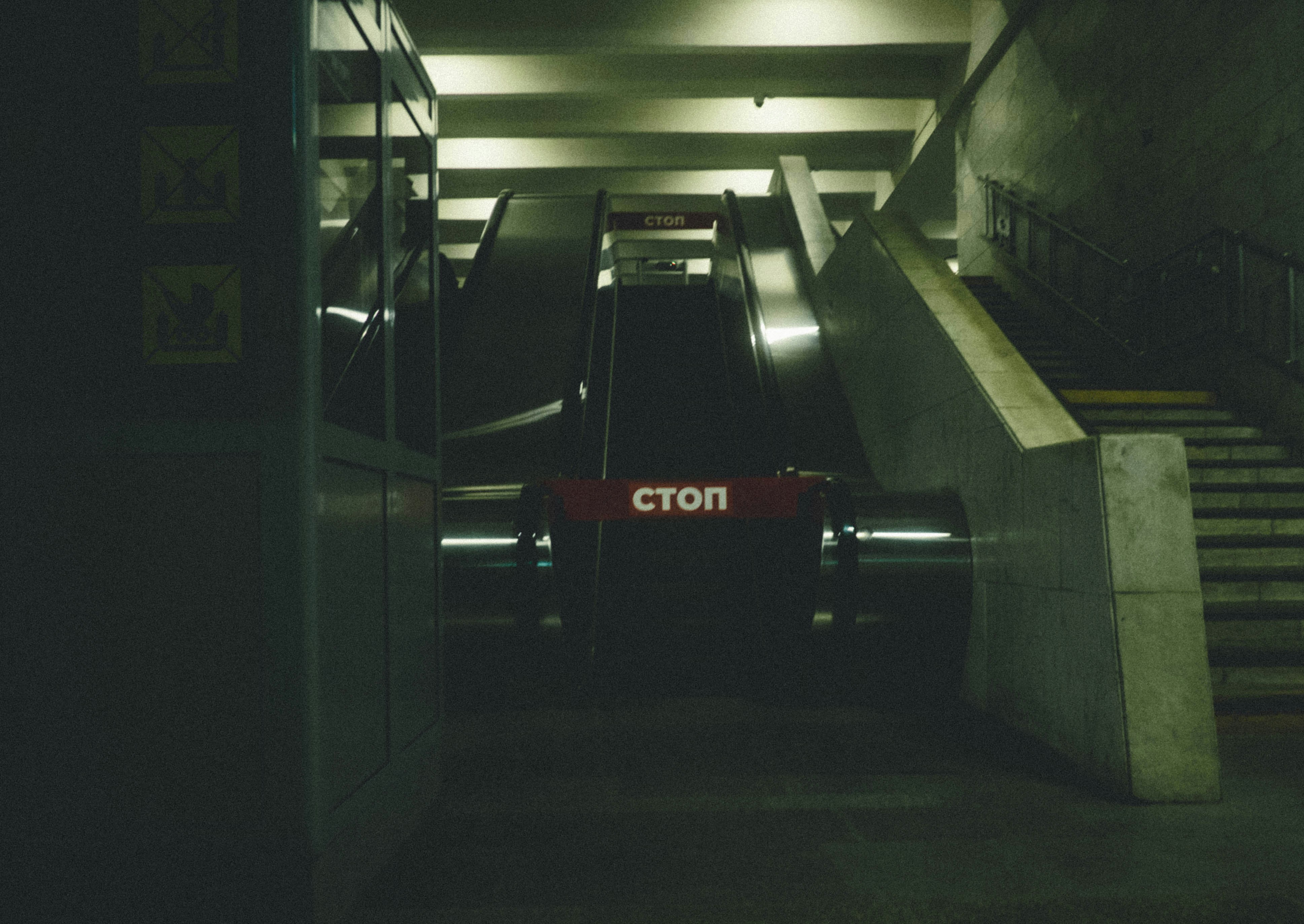 Escalator in a dark subway station with stop sign