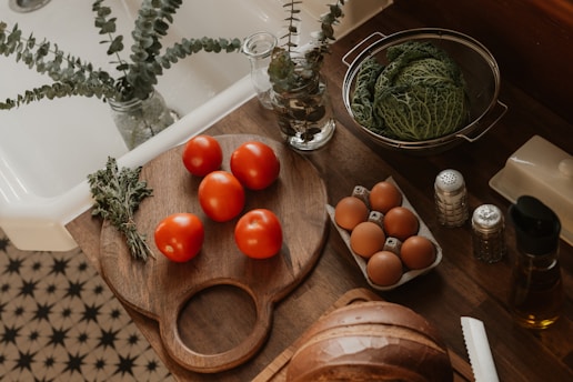 Tomatoes, eggs, and cabbage on a kitchen counter.