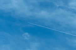 Airplane contrail across a clear blue sky.