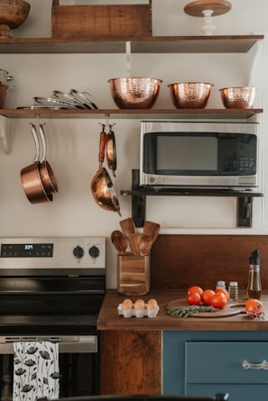 Kitchen counter with tomatoes, eggs, and utensils.