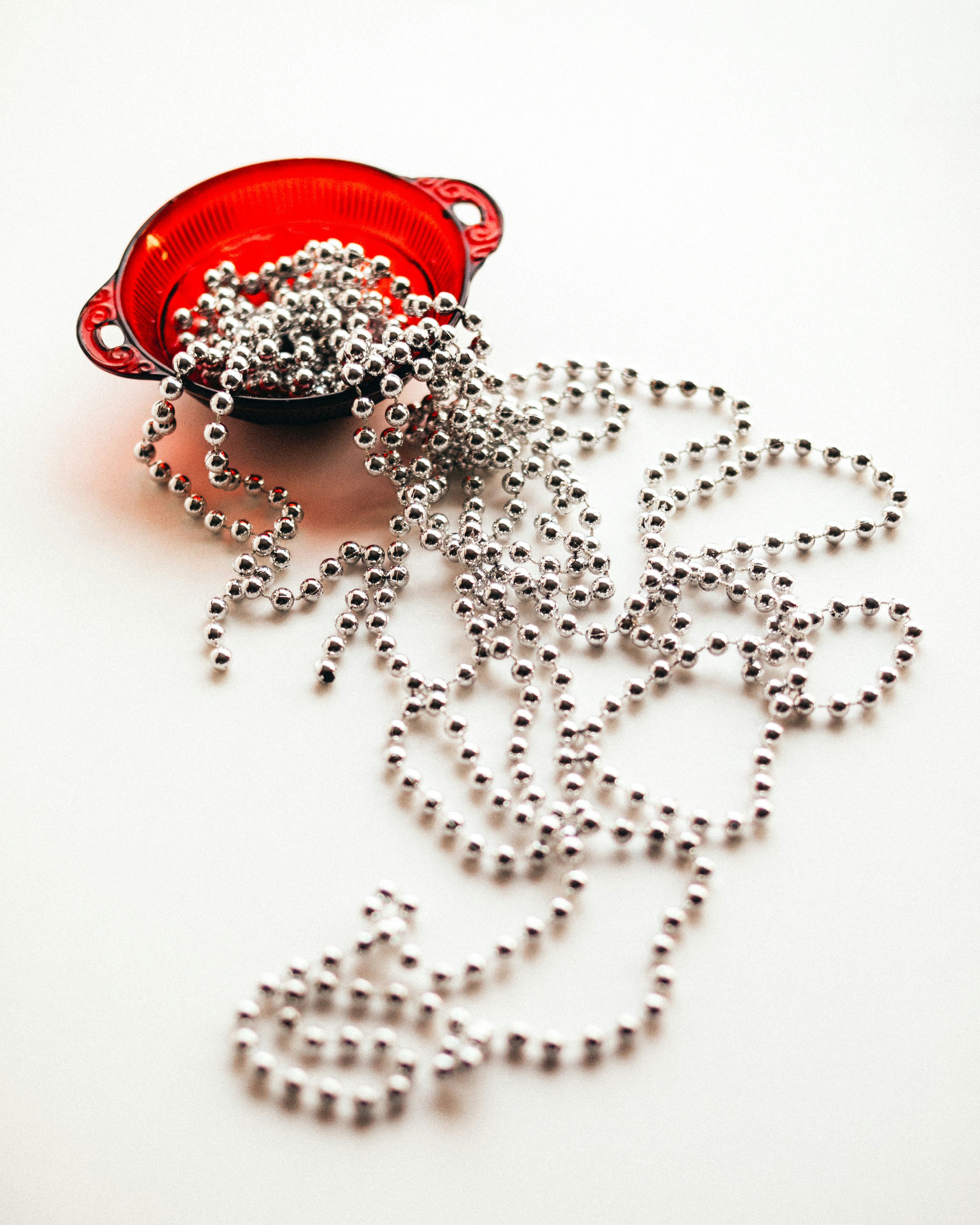 Silver beads spilling from a red bowl