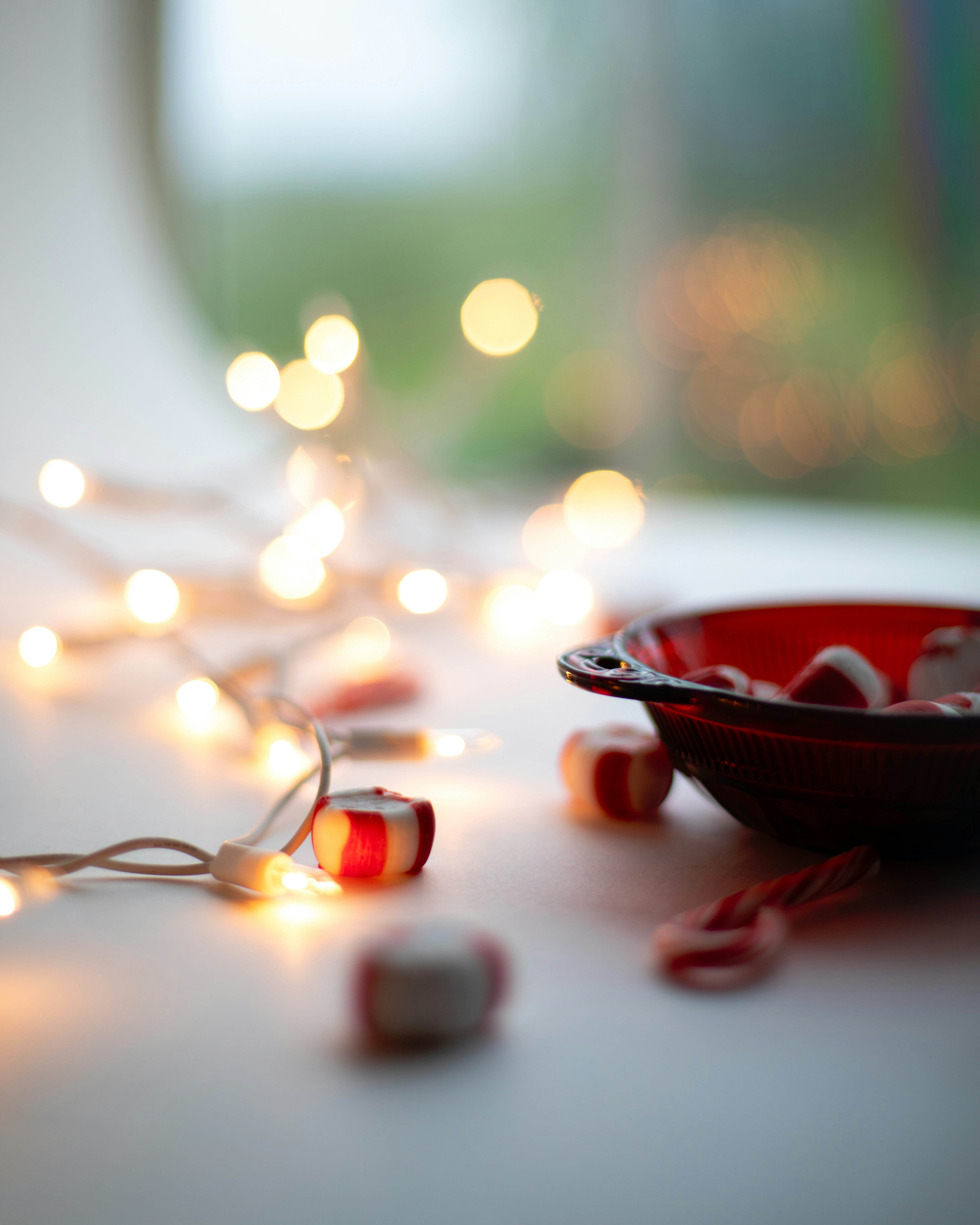 Red bowl filled with peppermint candies and string lights