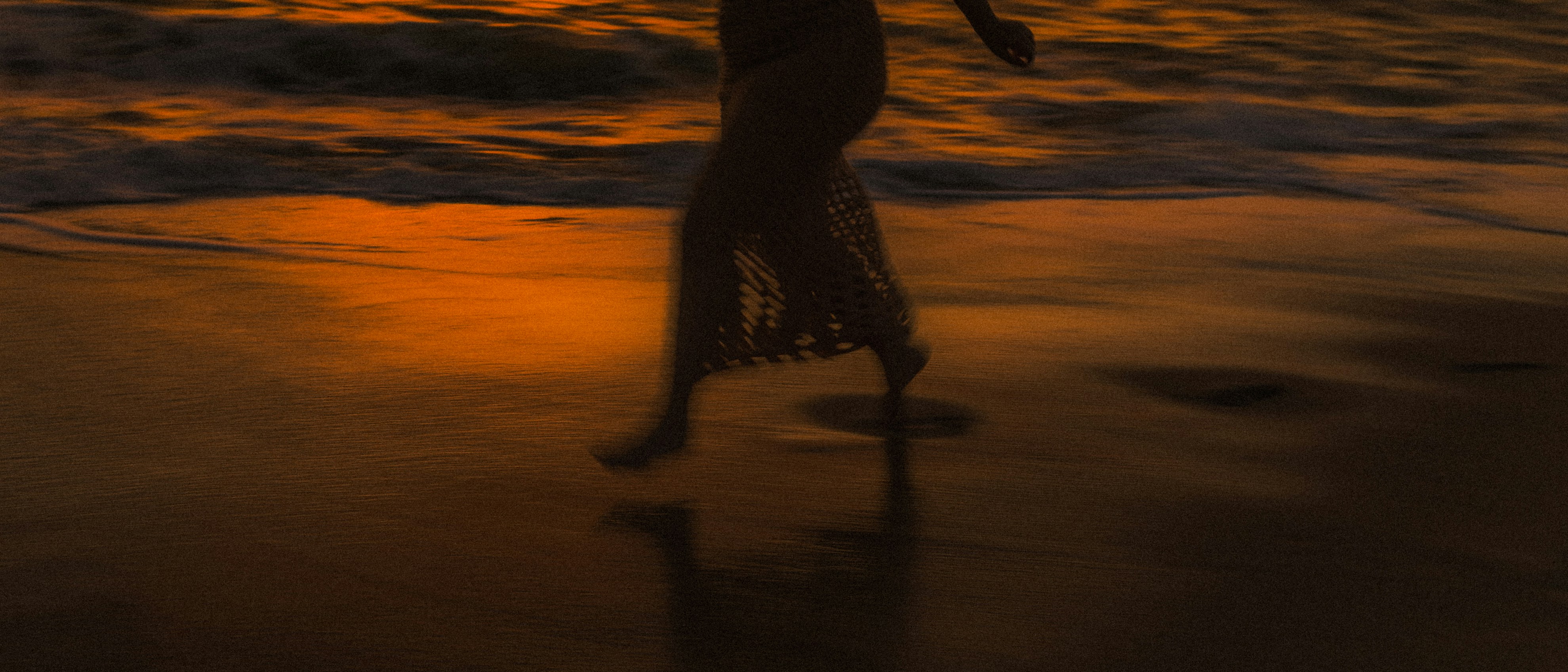 Woman walking on beach at sunset