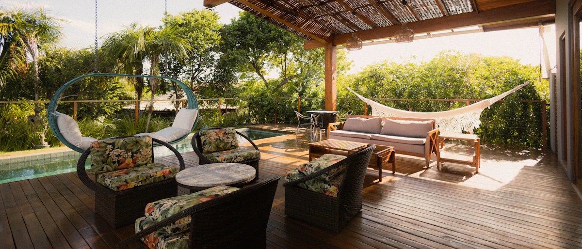 Covered lodge patio with seating, hammock, and pool view