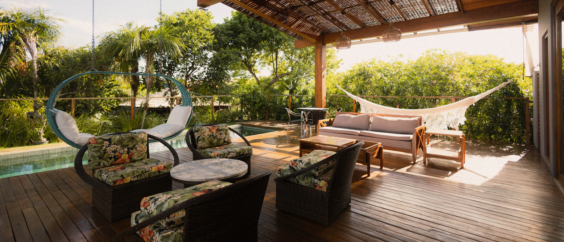 Covered backyard patio with seating, hammock, and pool view