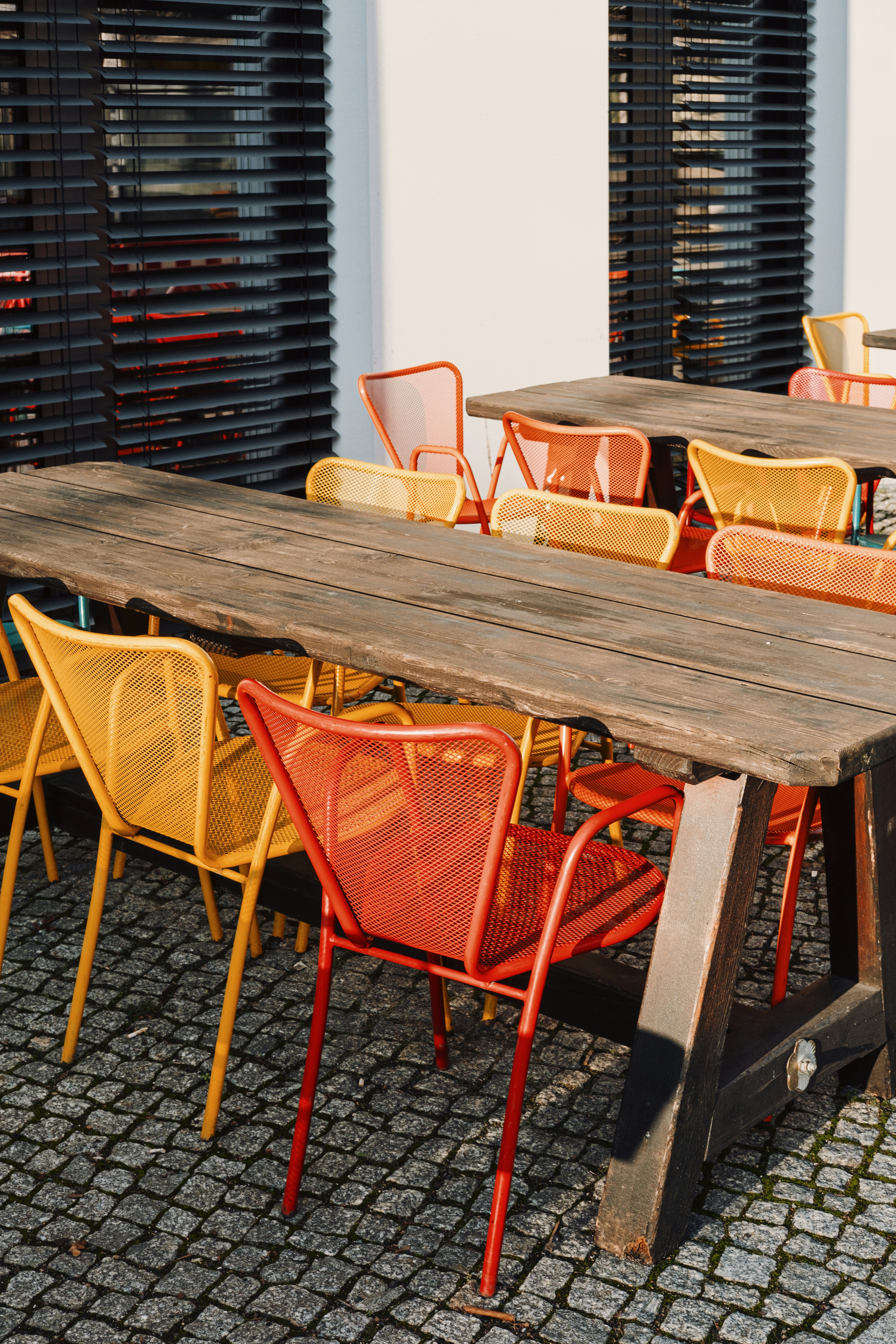 Colorful chairs around wooden tables outdoors