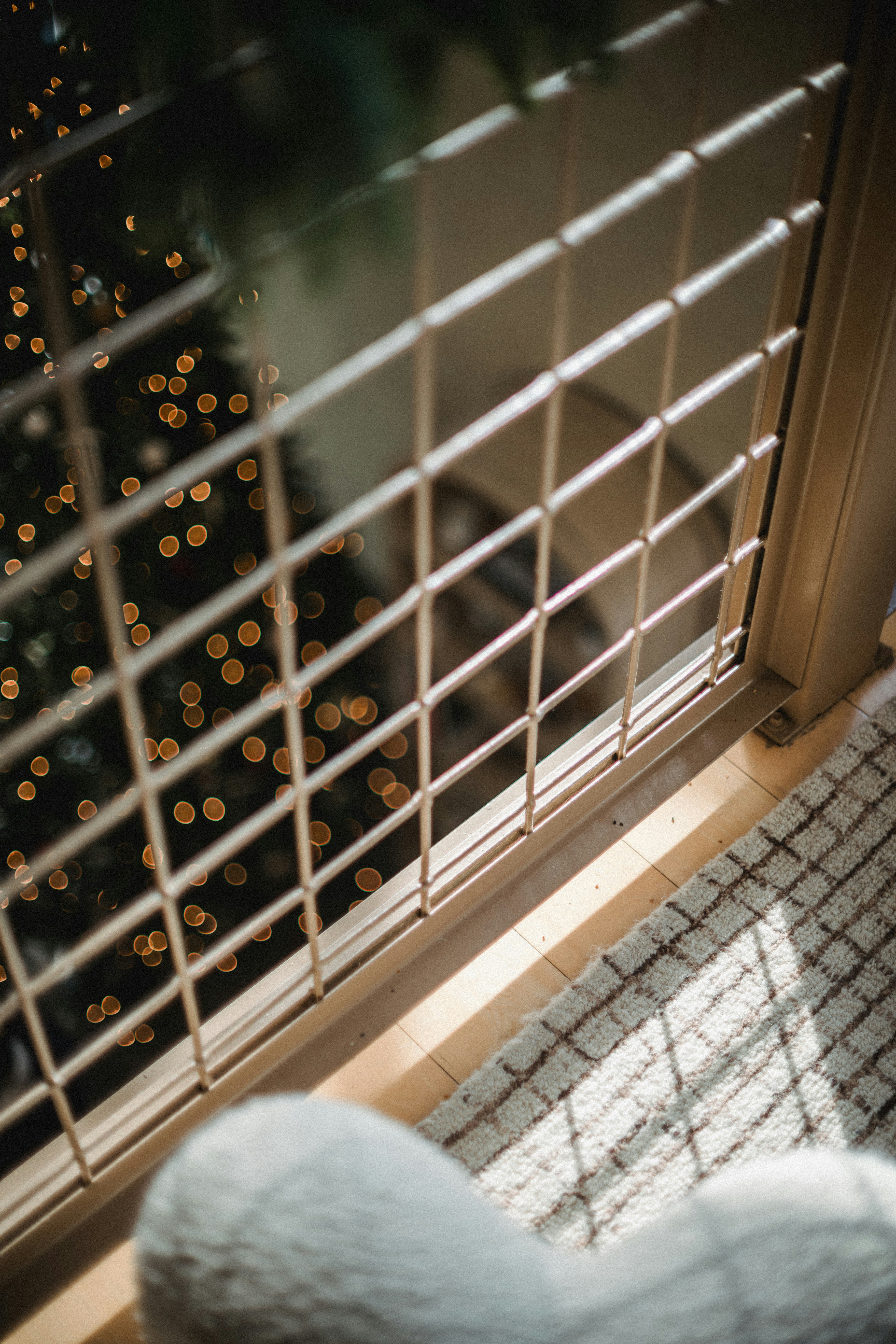 Blurred christmas tree lights seen through window blinds.