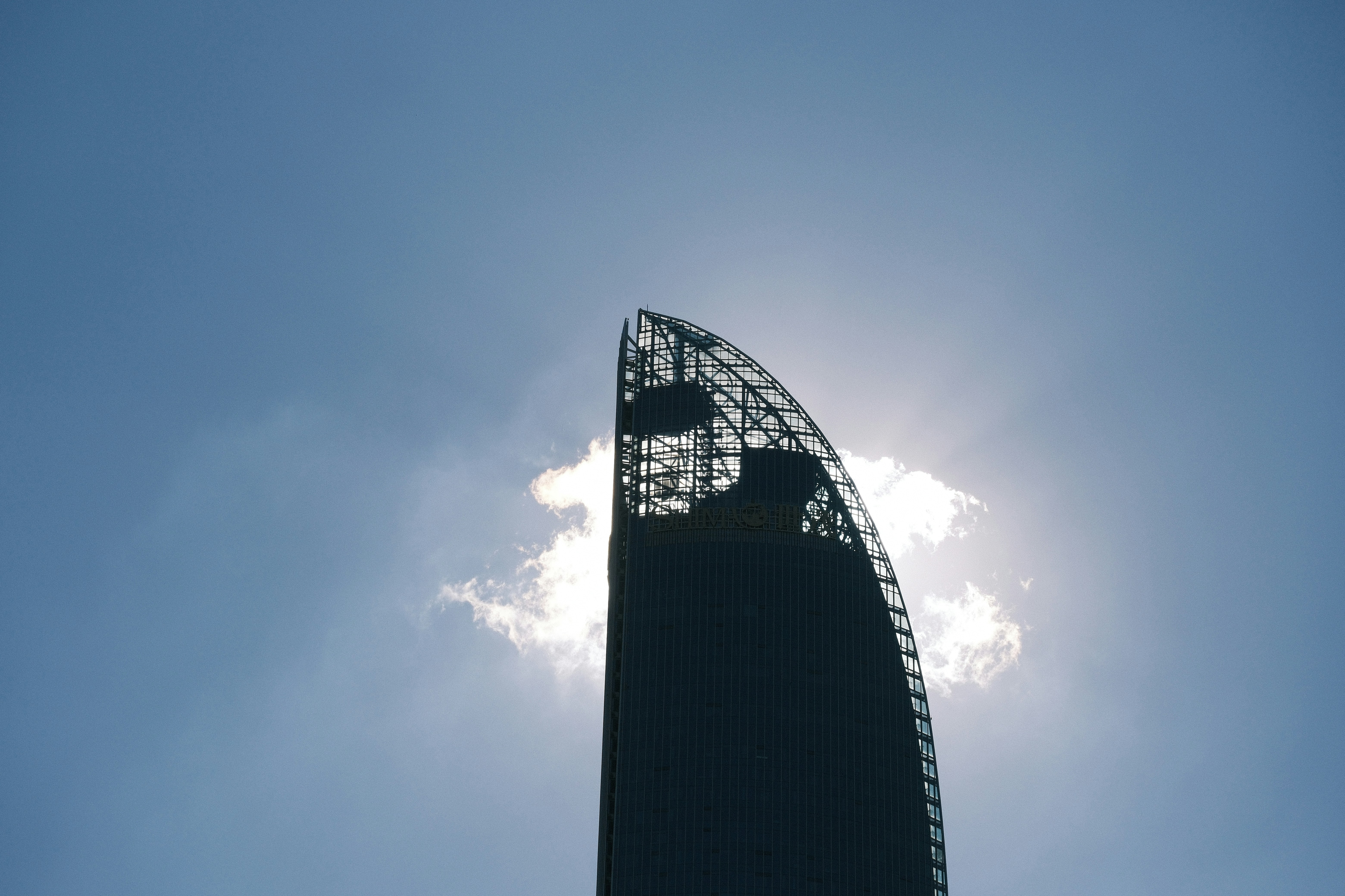 Silhouette of a modern skyscraper against a bright sky.