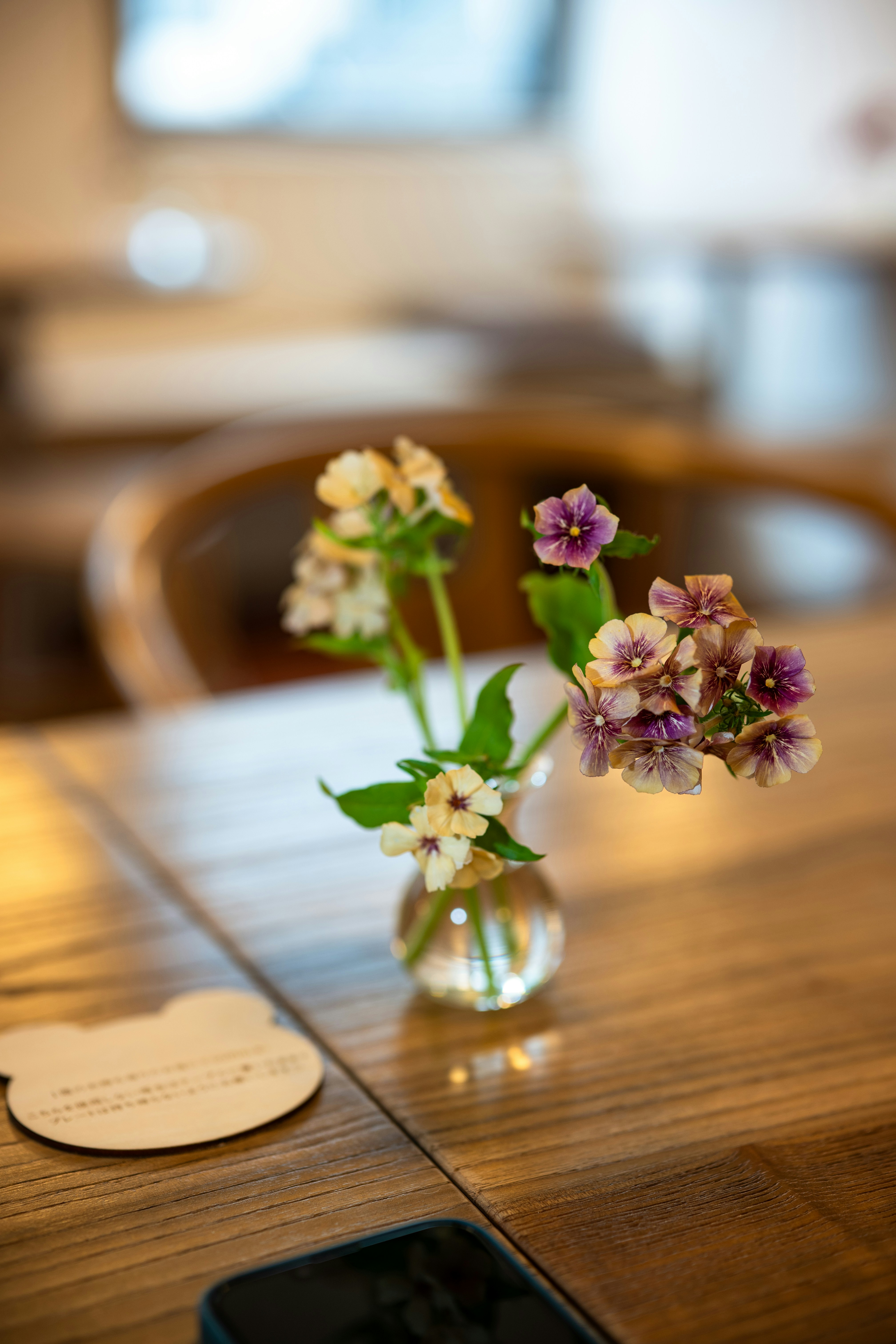 Small vase with flowers on a wooden table.