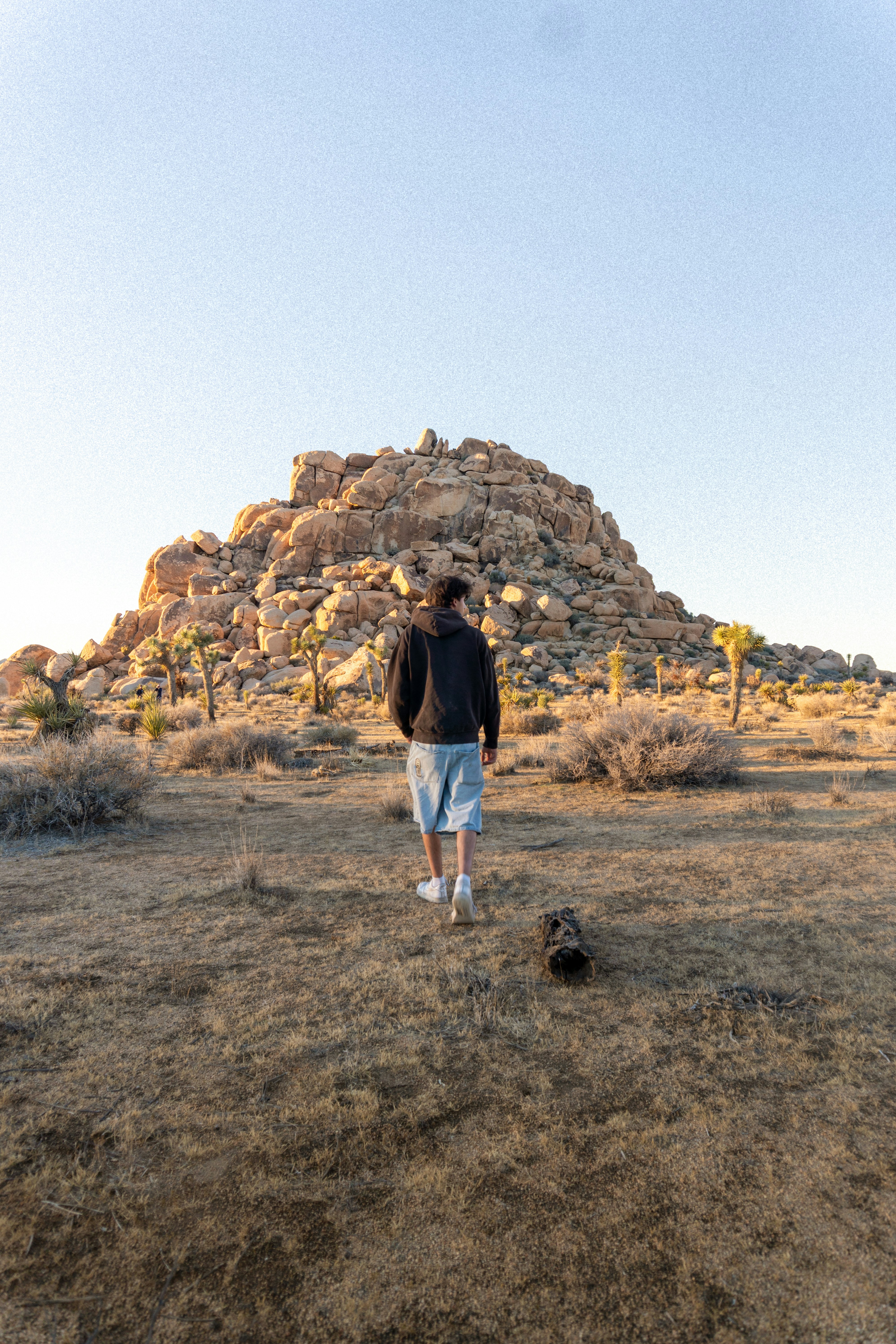 El hombre camina hacia una colina rocosa en un paisaje desértico