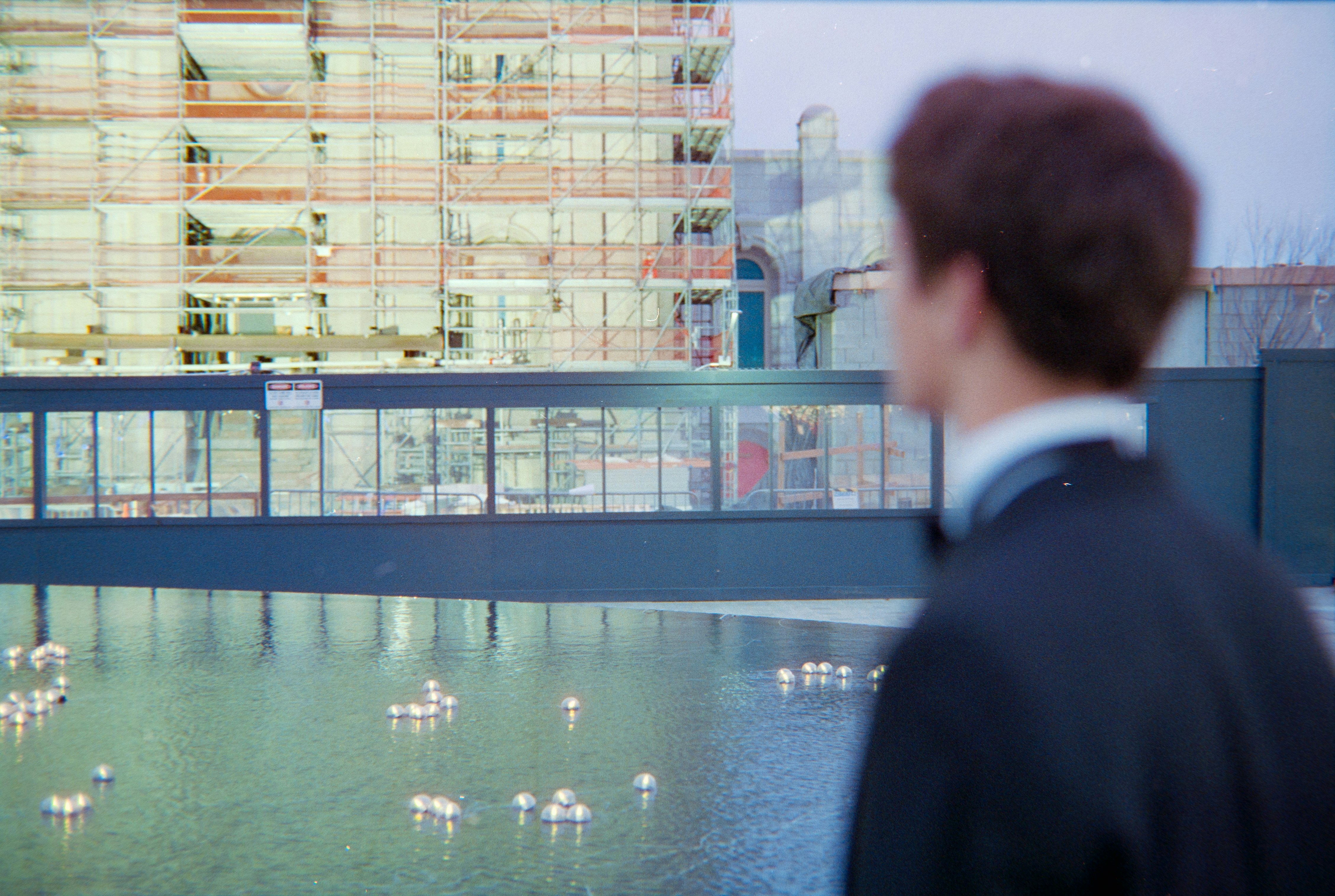 Man in suit looks at building under construction.