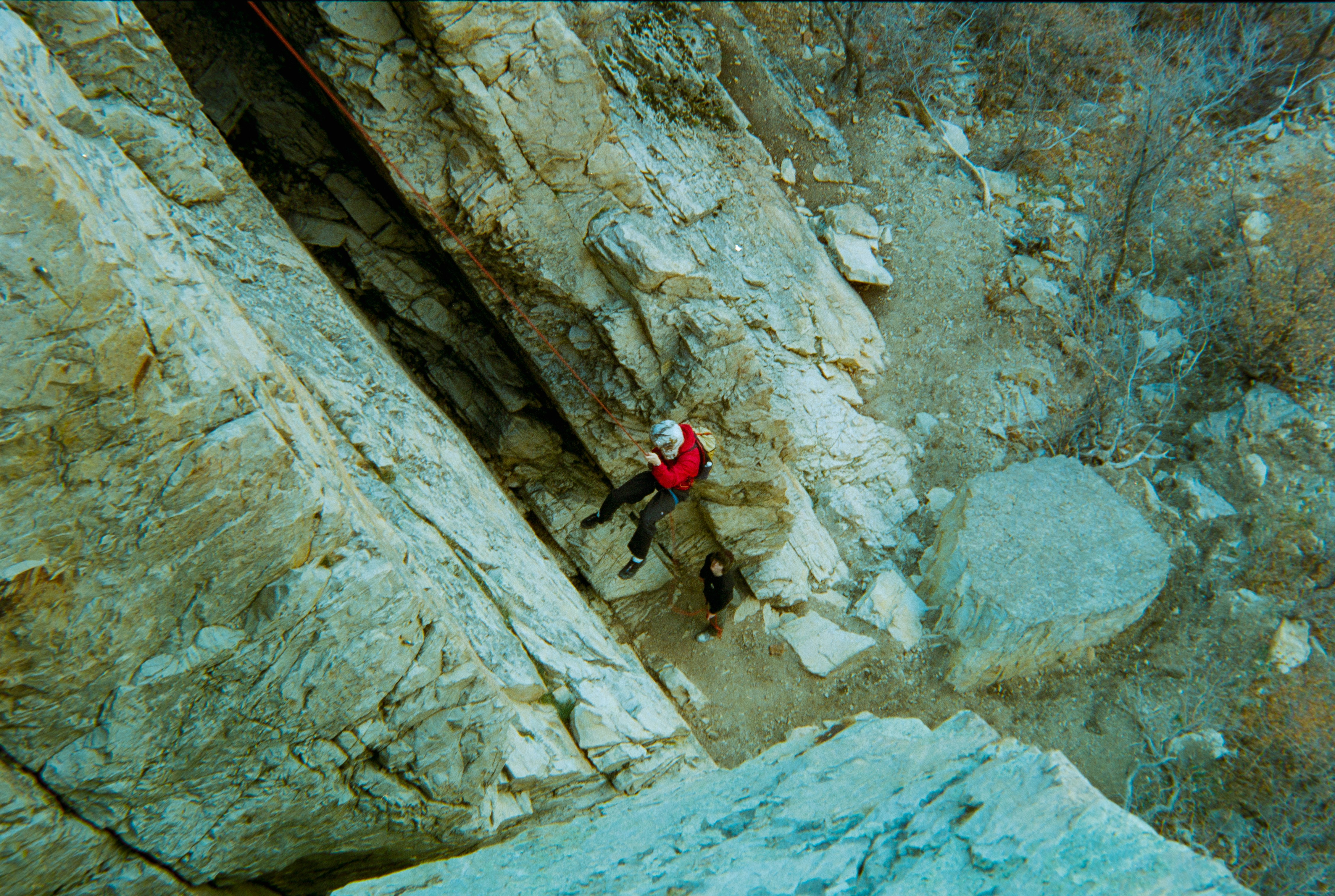 Climber rappels down a steep rocky cliff face.