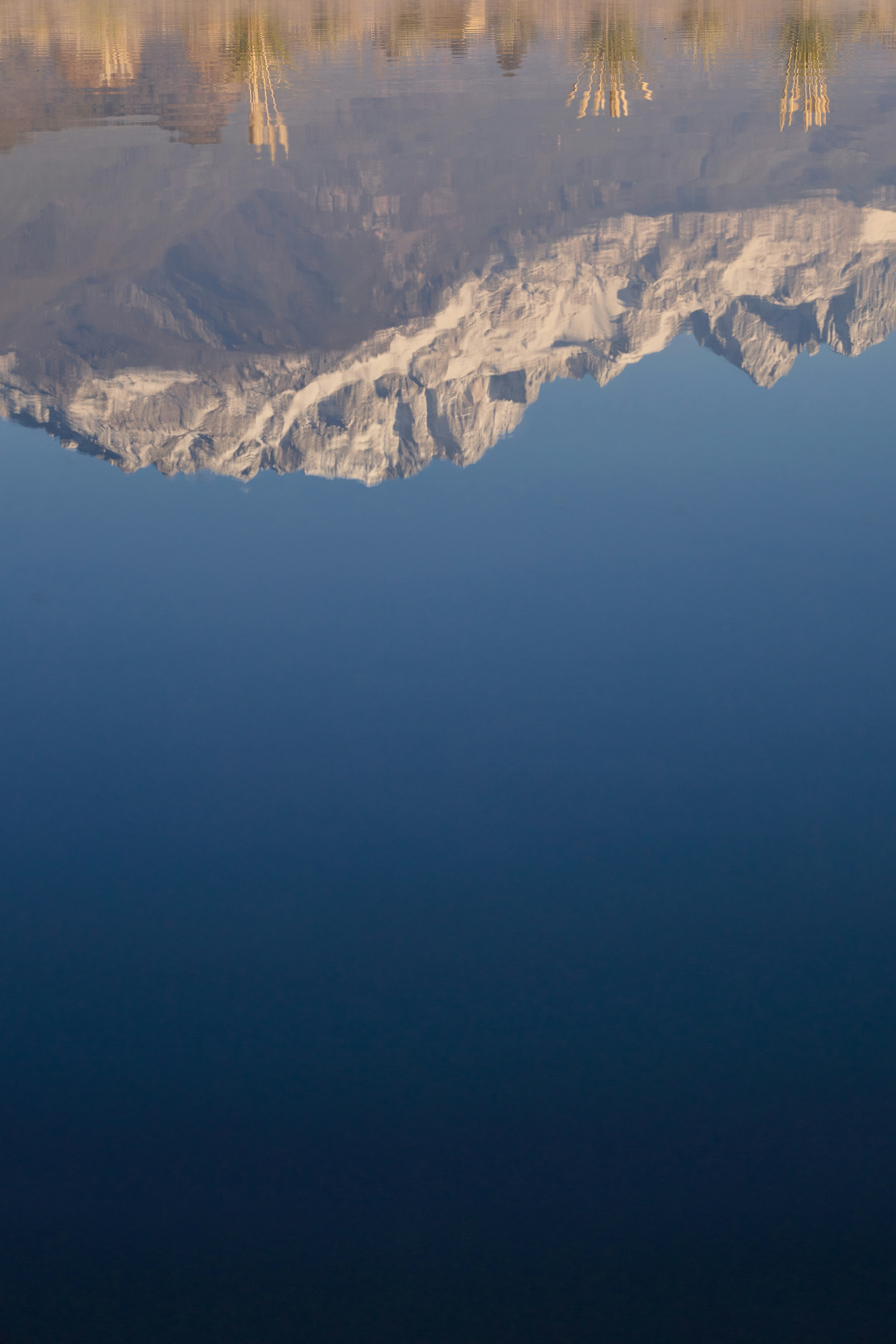 Schneebedeckte Berge spiegeln sich in ruhigem blauem Wasser wider