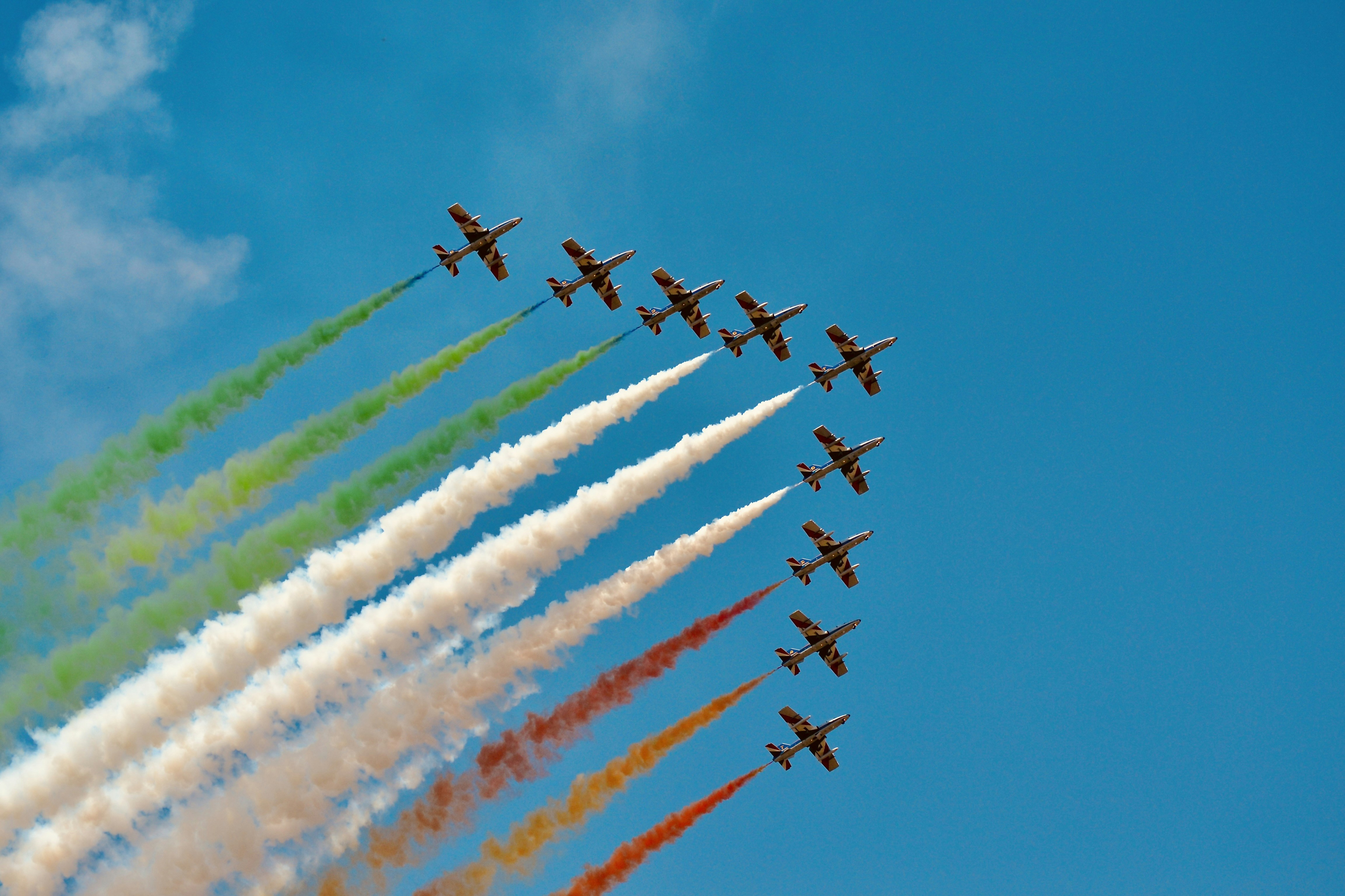 Fighter jets fly in formation, leaving colorful smoke trails.