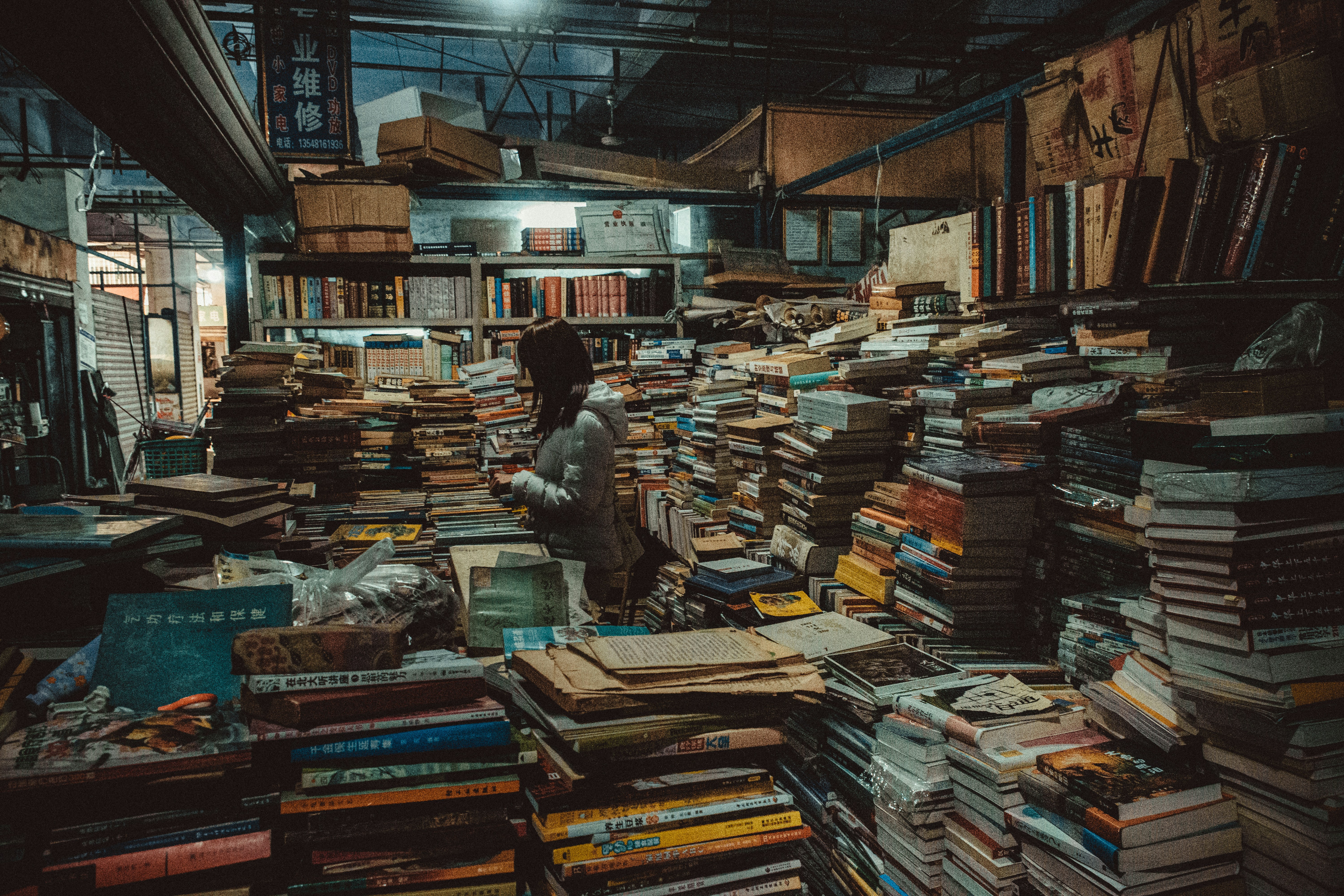 Person browsing through stacks of old books