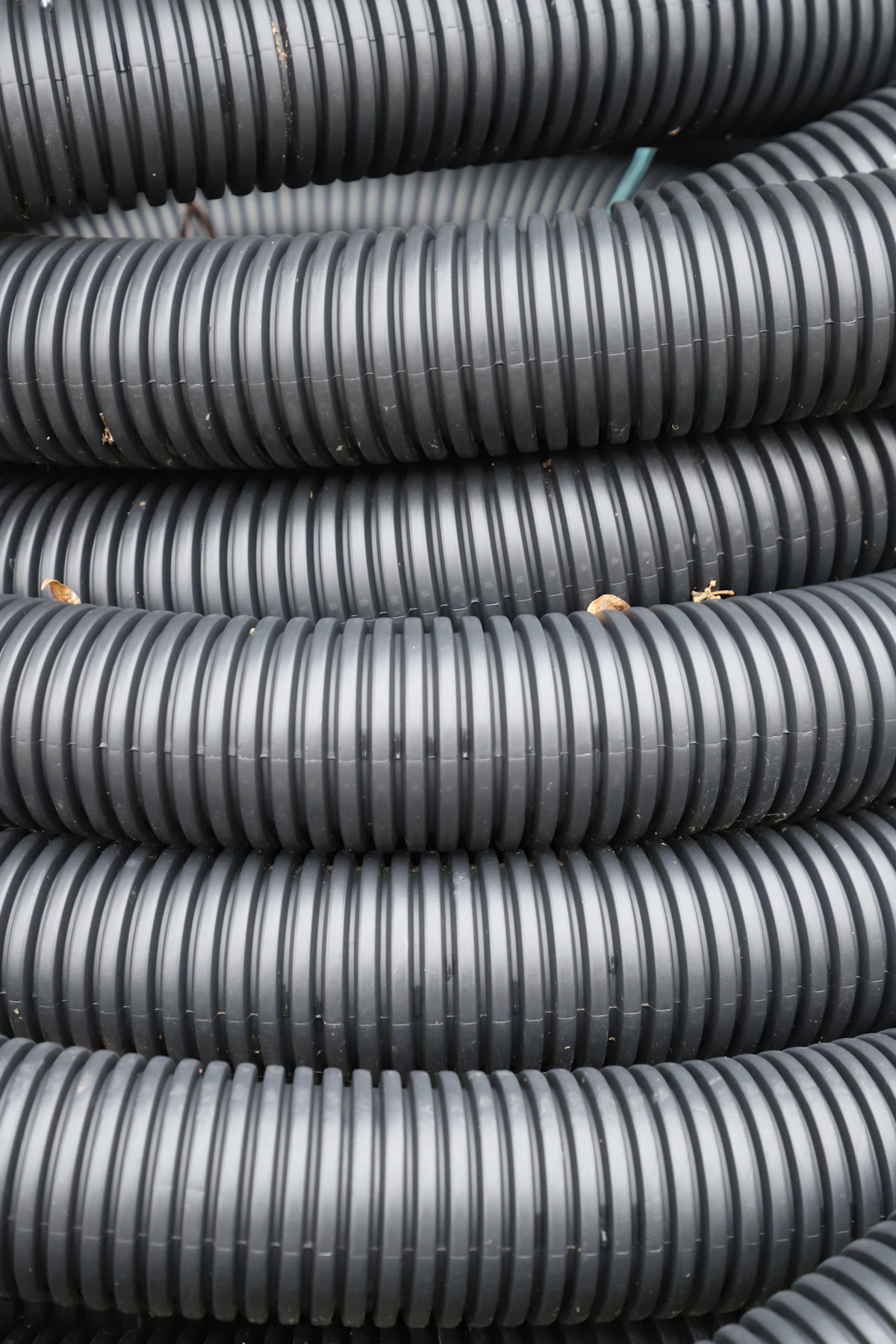 Close-up of stacked black double-wall corrugated (DWC) drainage pipe showing ribbed wall texture