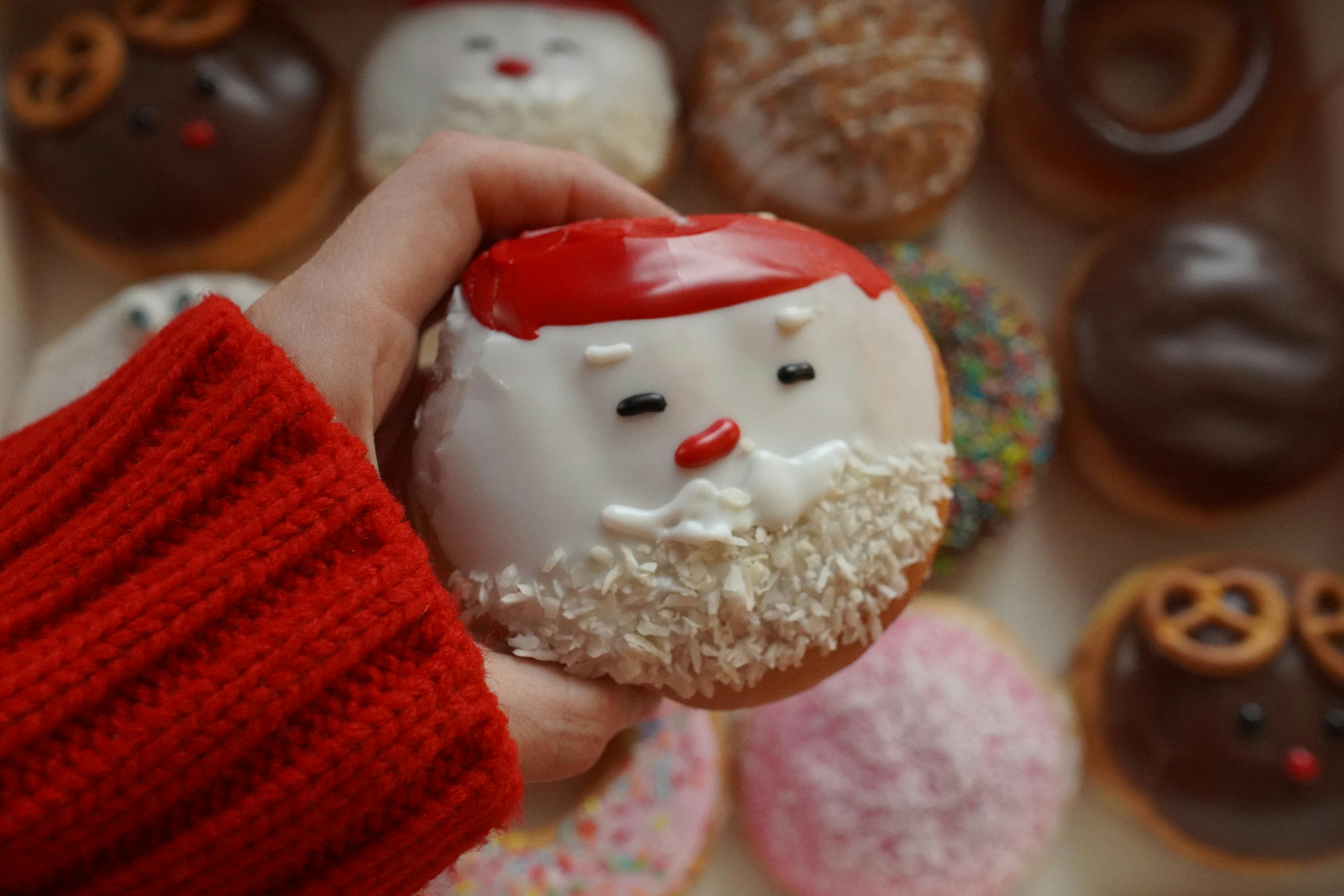 Hand holding a santa claus donut with other donuts