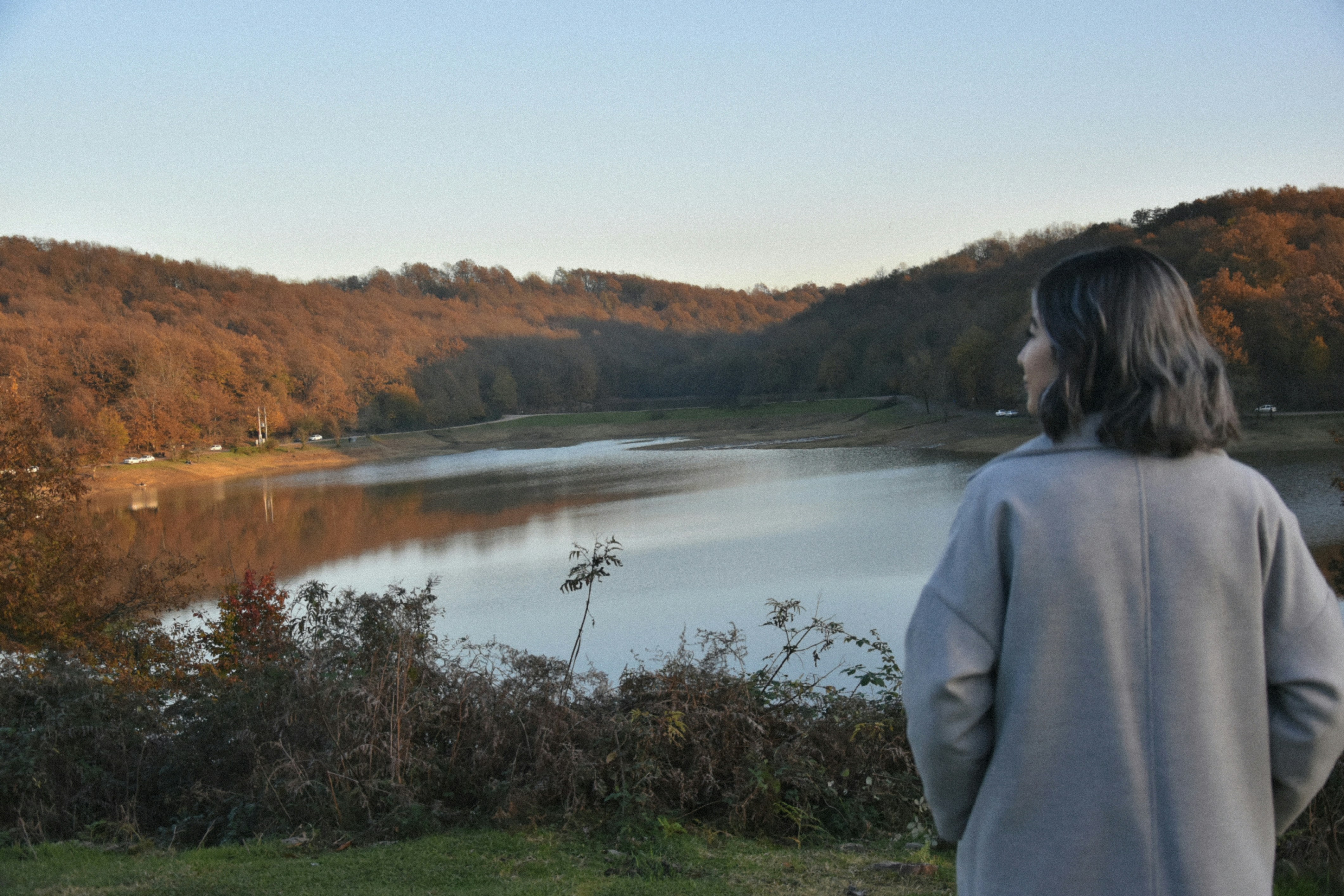 Woman looking at a tranquil lake and wooded hills