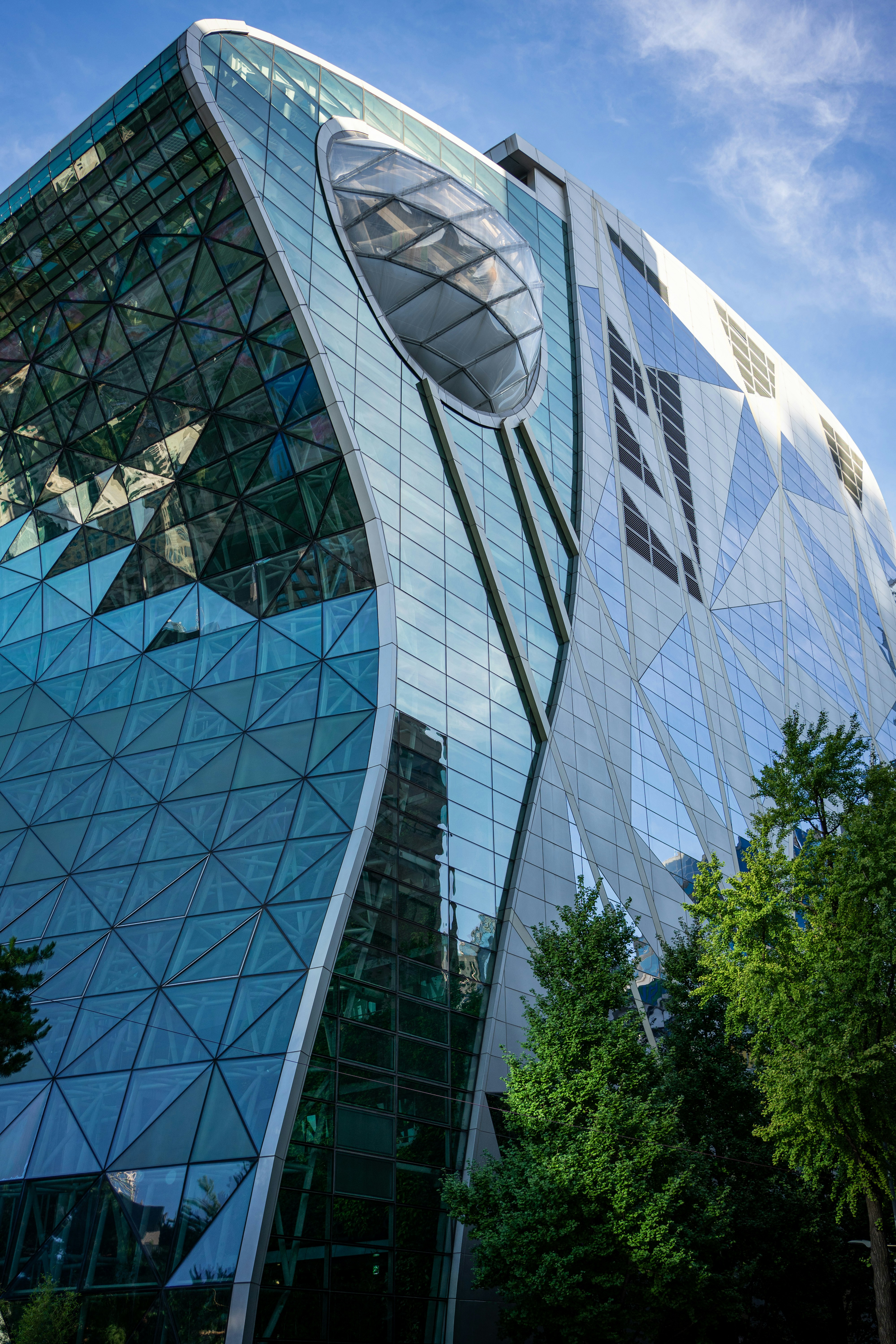 Modern glass building with geometric facade and trees
