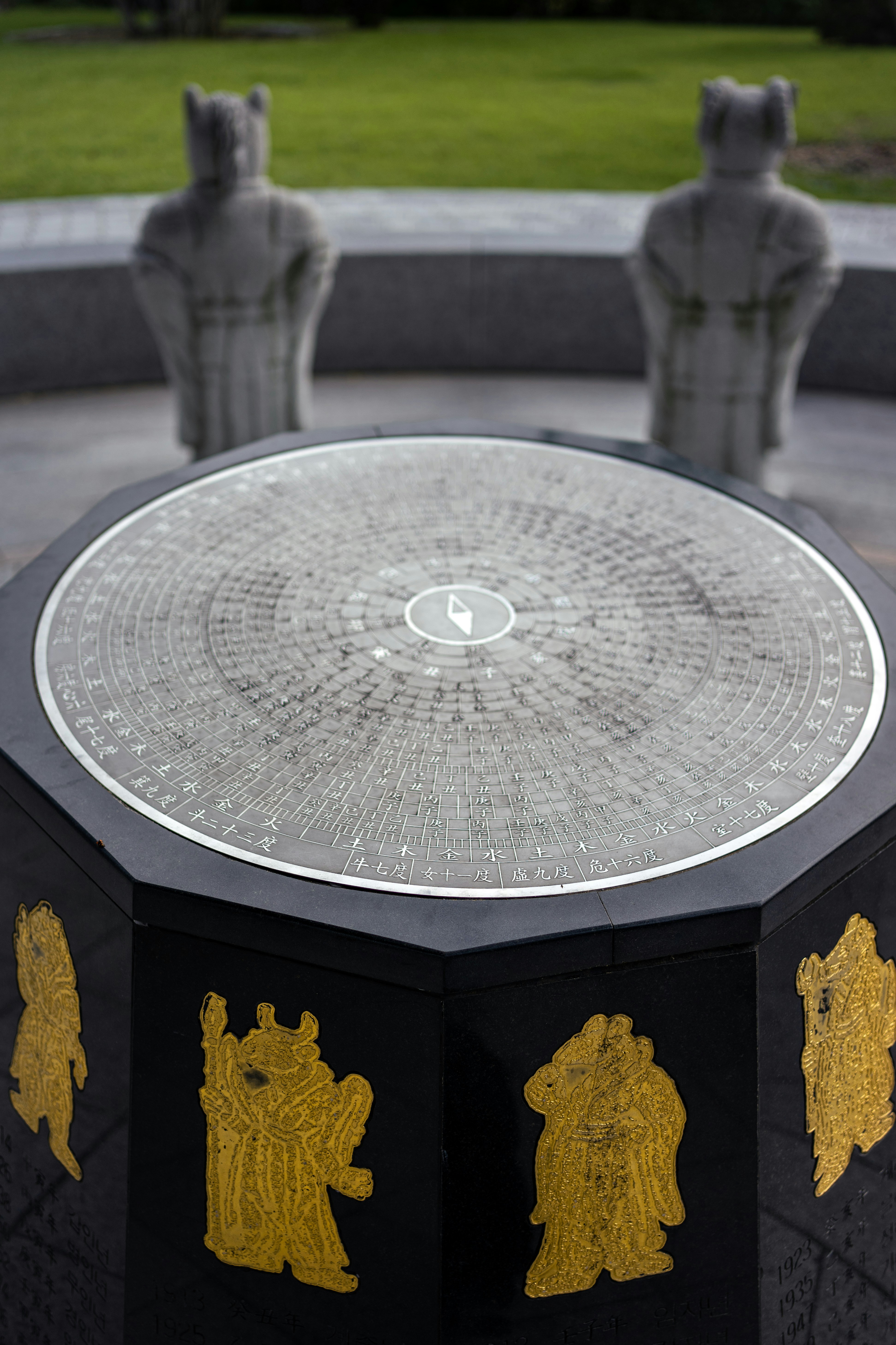 Stone statues stand behind a detailed octagonal monument