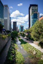 Cityscape with a stream and lush green trees.