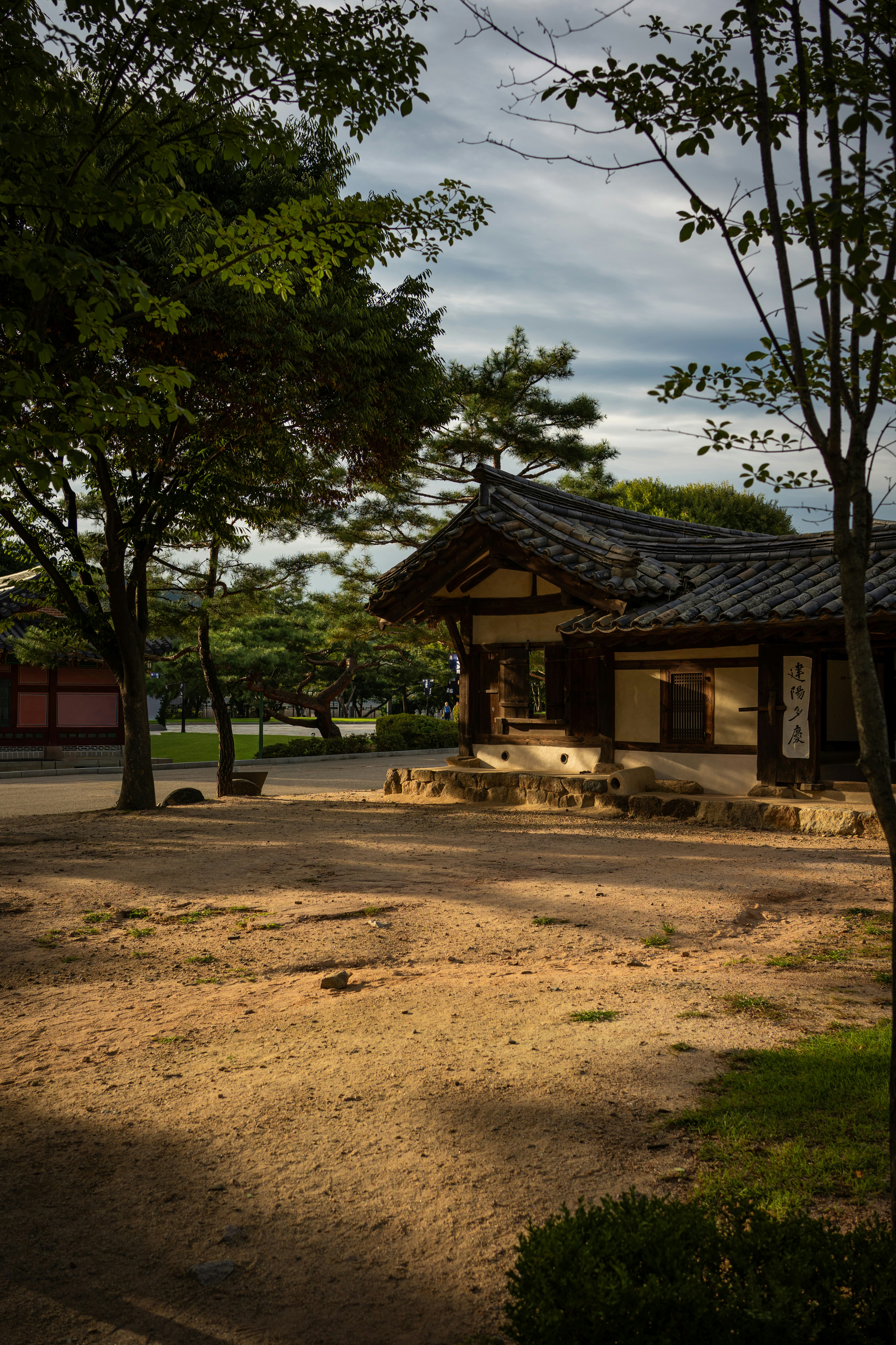 Traditional korean house with tiled roof and trees.