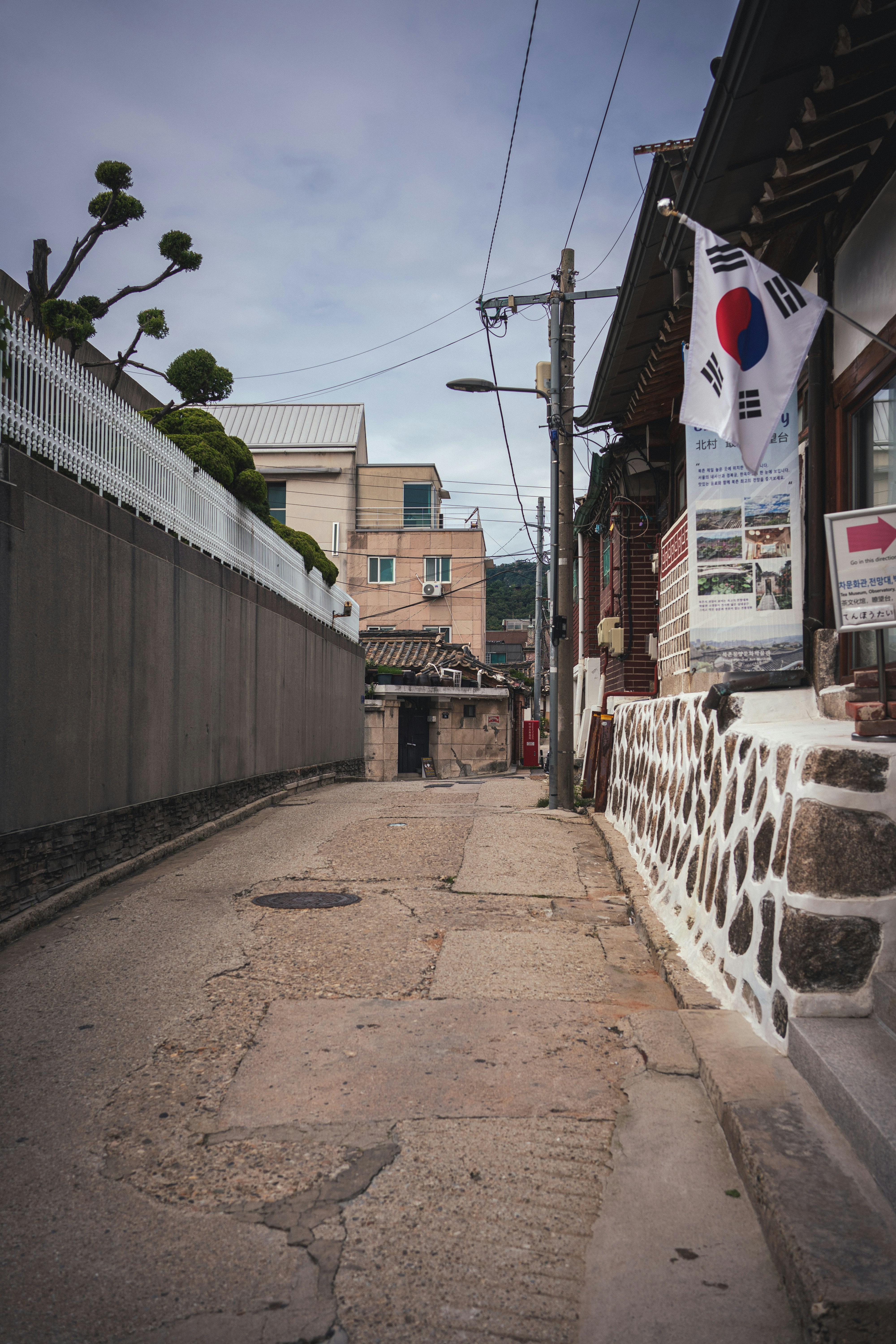 A narrow street with traditional korean buildings and flag.