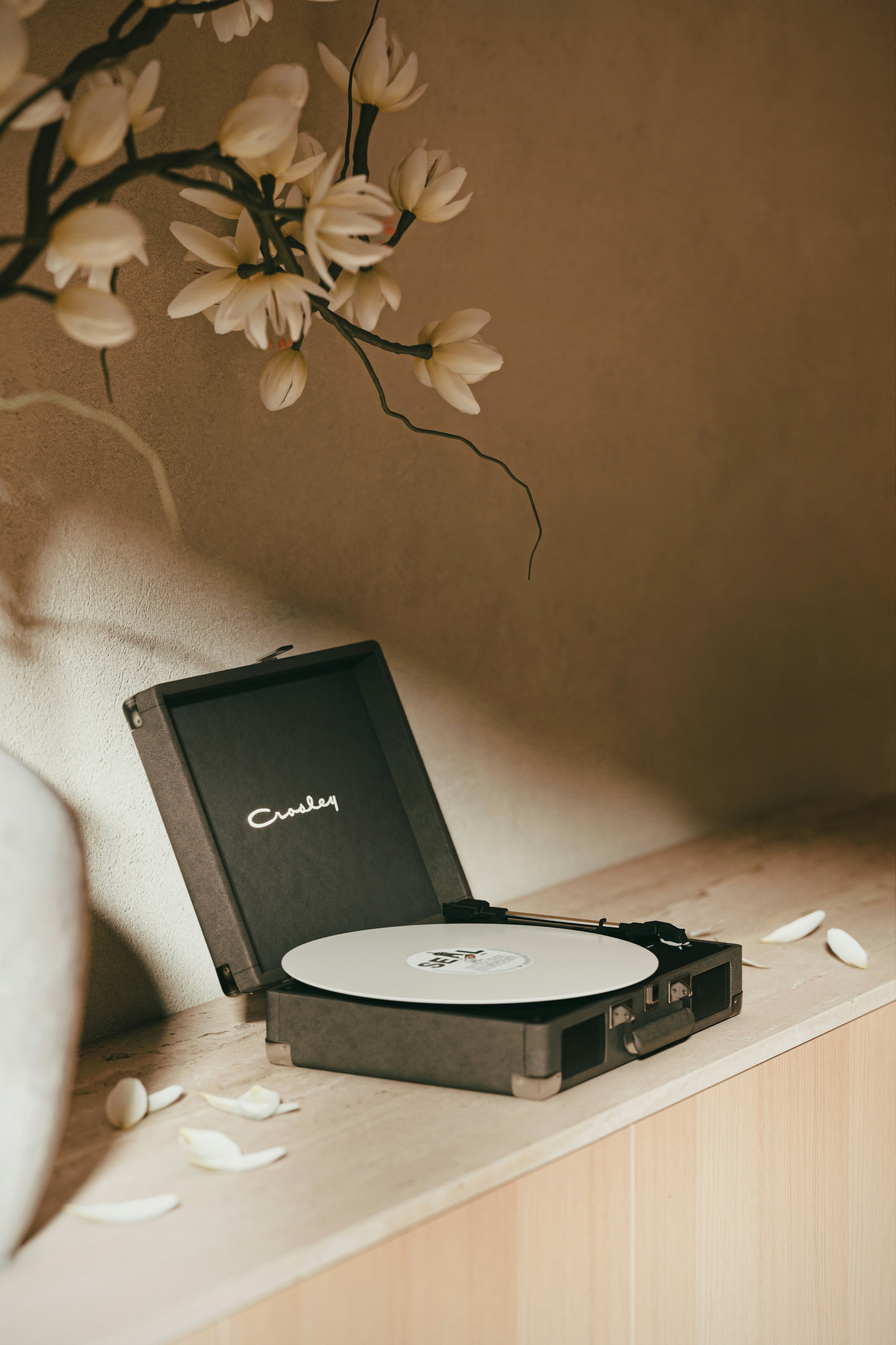 Vintage record player with white petals on shelf